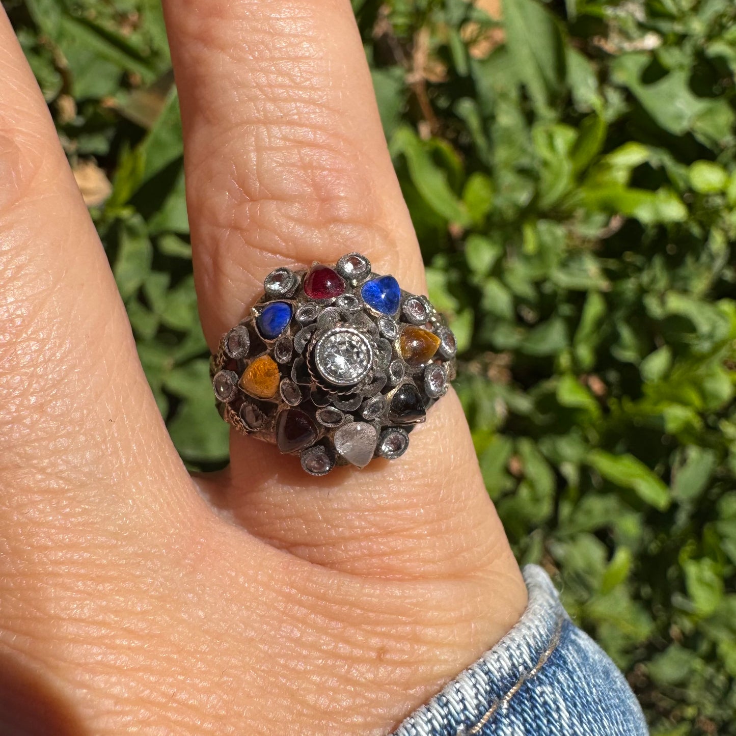 14K gold ring set with a central transparent gemstone surrounded by a vibrant mosaic of colorful gemstones -set in an ornate, handcrafted design