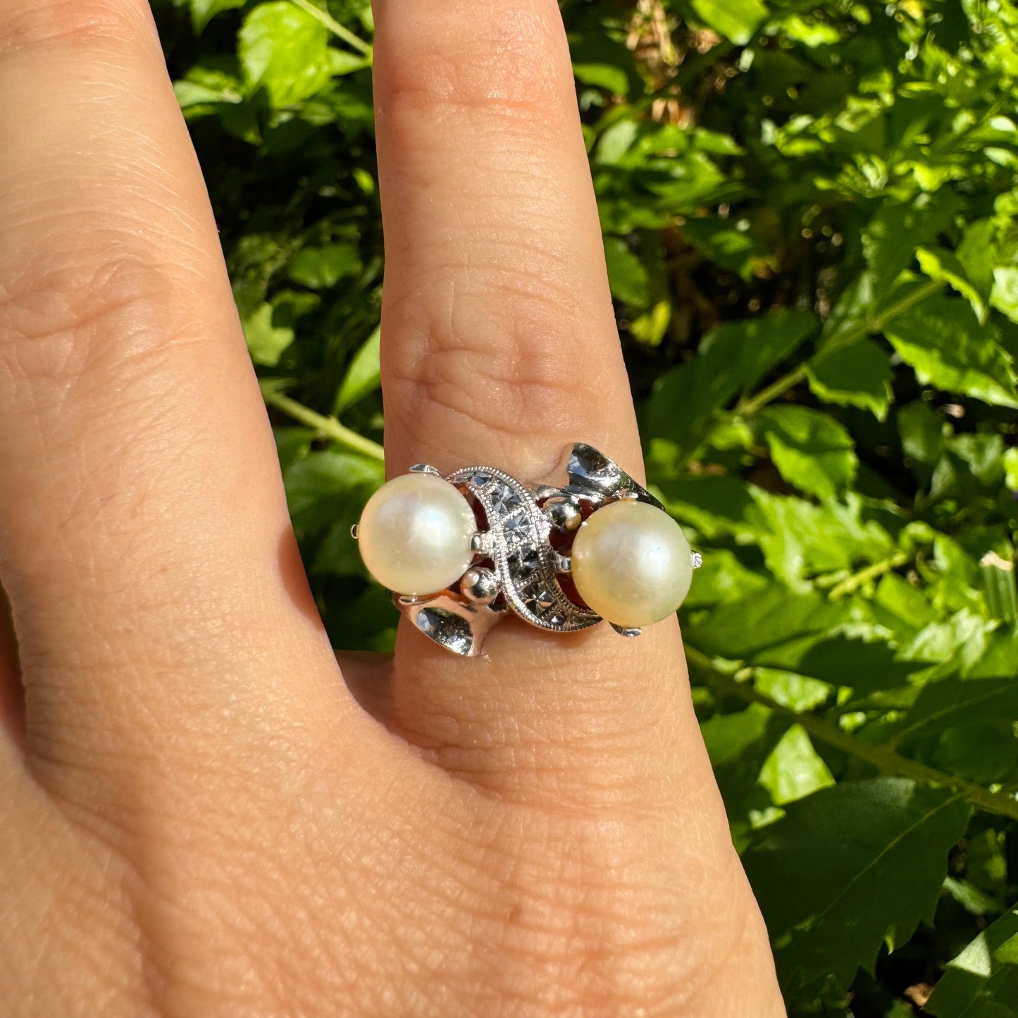 14K gold ring featuring two round white pearls set side by side, accented with a small decorative detail between them & Diamonds