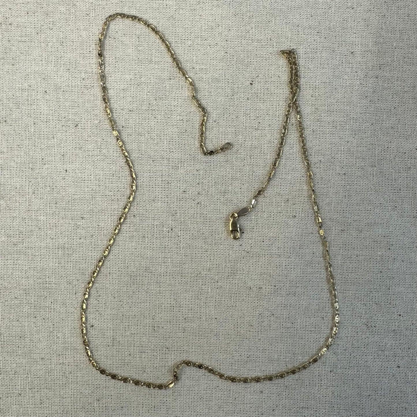 14K gold necklace featuring oval-shaped links with a subtle decorative pattern.