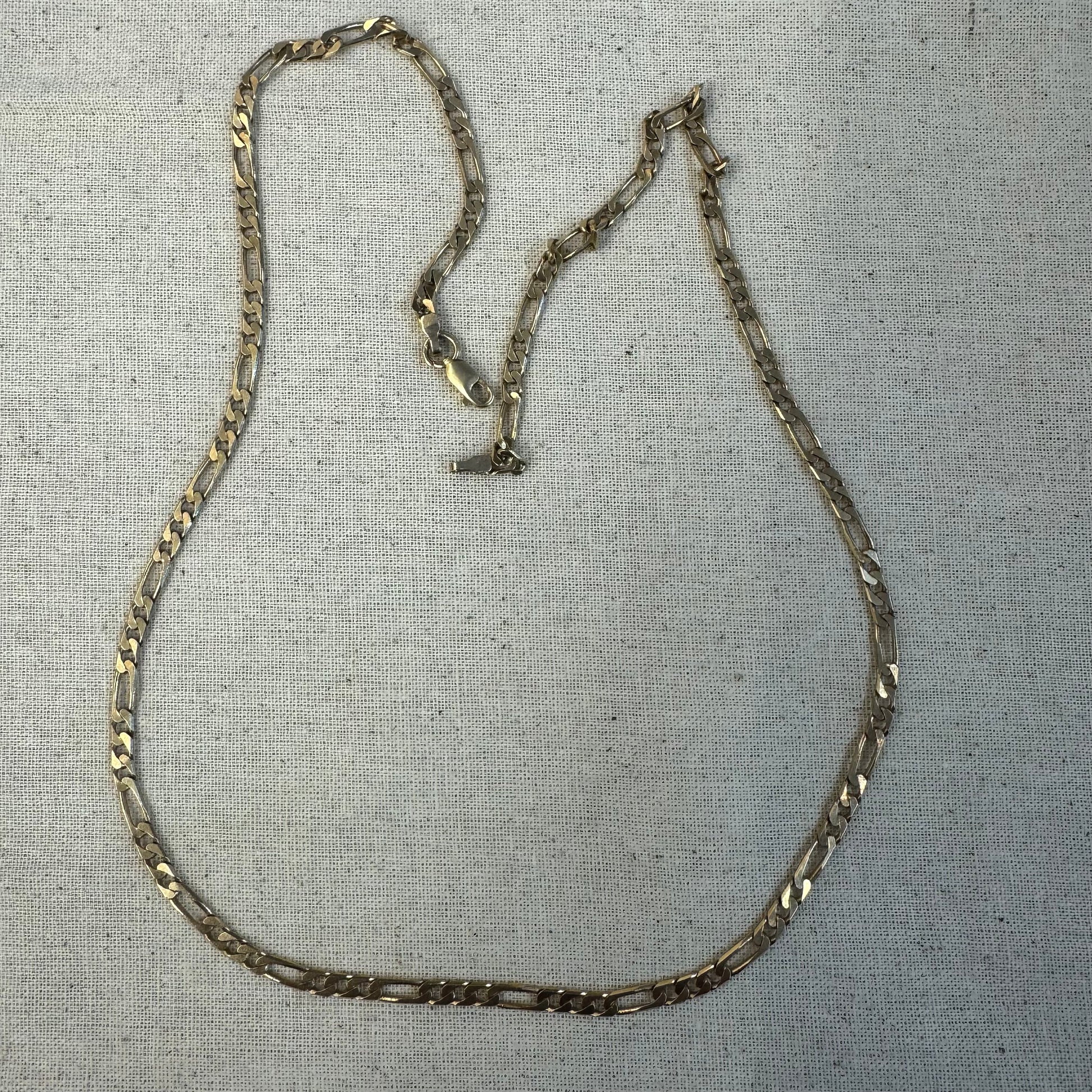 שרשרת זהב 14 קראט בסגנון Figaro chain – עיצוב קלאסי שבו חוליות קצרות מתחלפות עם חוליה אחת ארוכה.