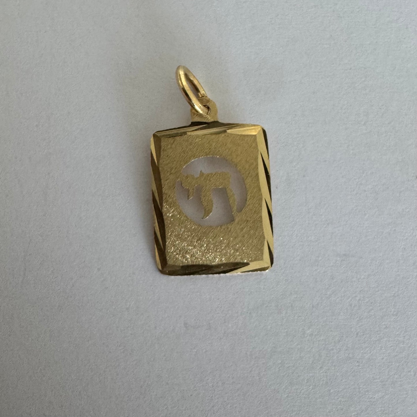 תליון זהב צהוב 14 קראט בעיצוב מלבני עם חריטה של סמל “חי”.