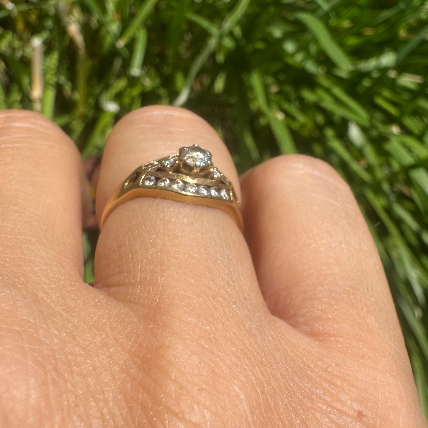 18K gold ring set with a central round Diamond, surrounded by rows of Diamonds in a decorative setting.