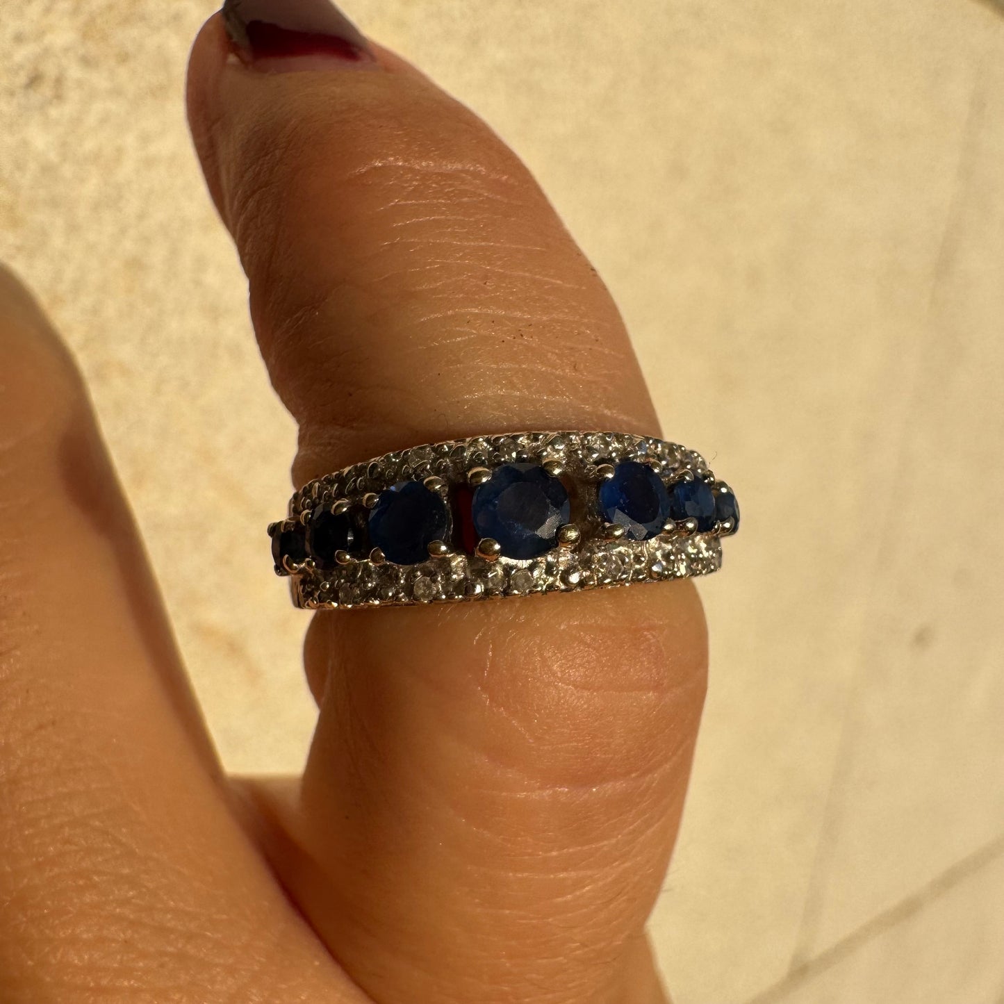 18K gold ring set with deep blue sapphires in a classic round cut, framed by two shimmering rows of brilliant Diamonds.