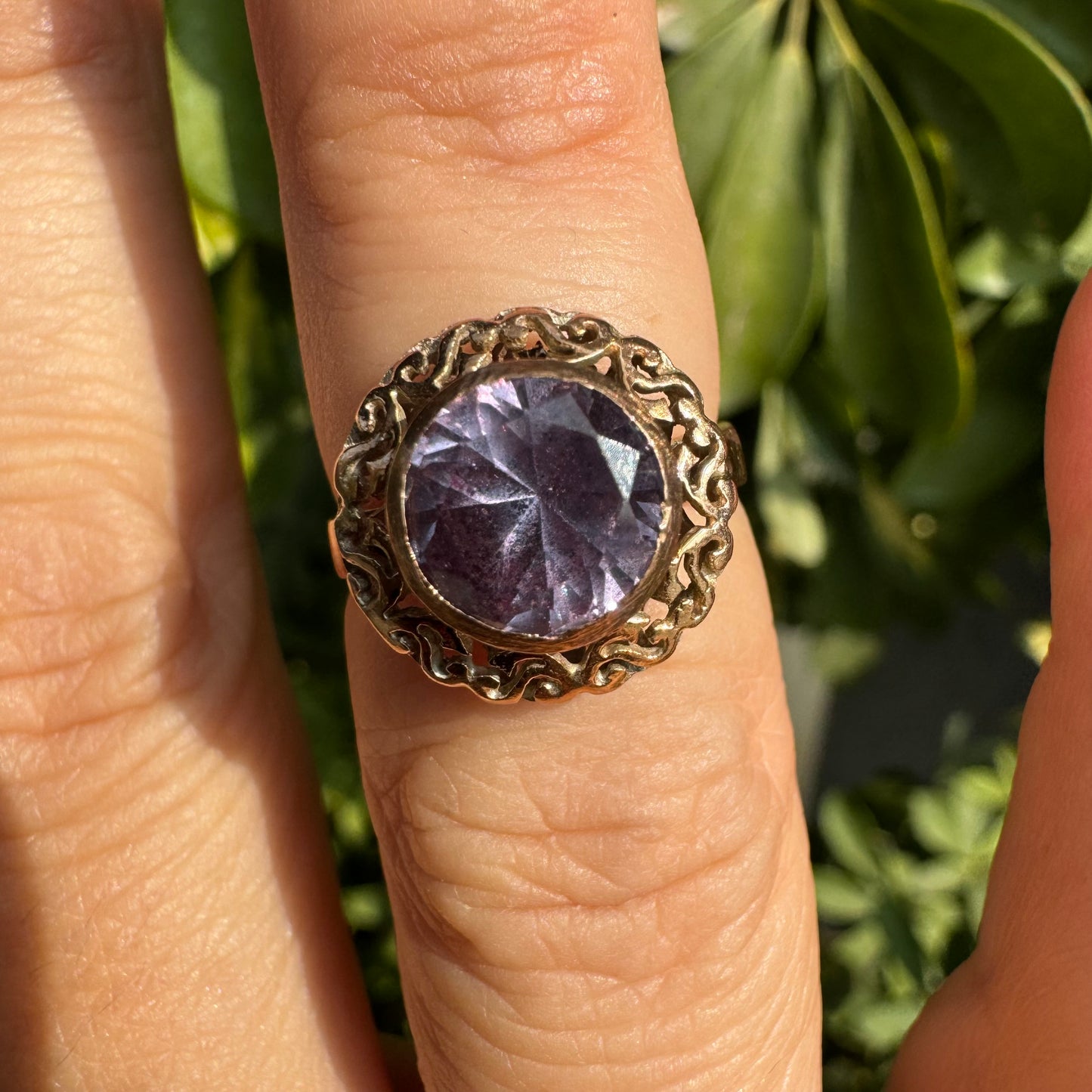 14K gold ring set with a large round-cut Tanzanite framed by an ornate filigree bezel