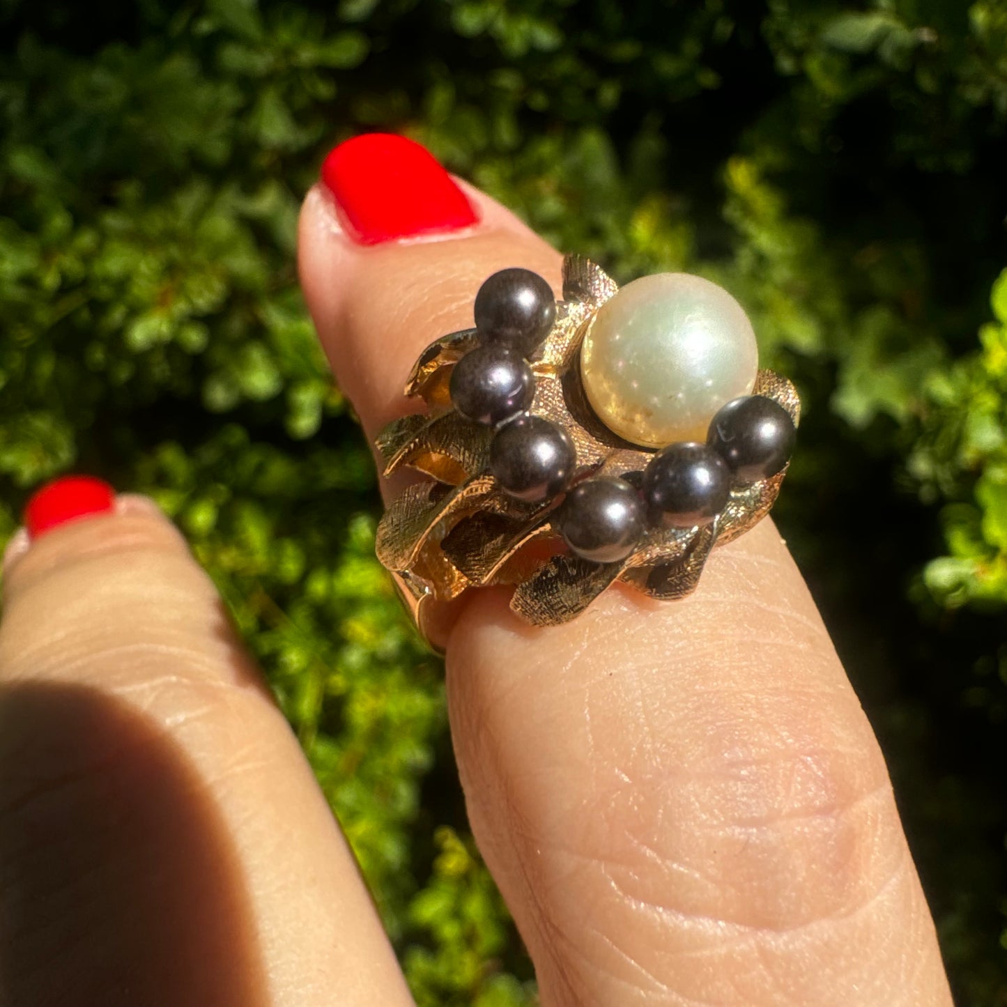 14K gold ring set with a luminous white Pearl at its center surrounded by a delicate circle of black Pearls.