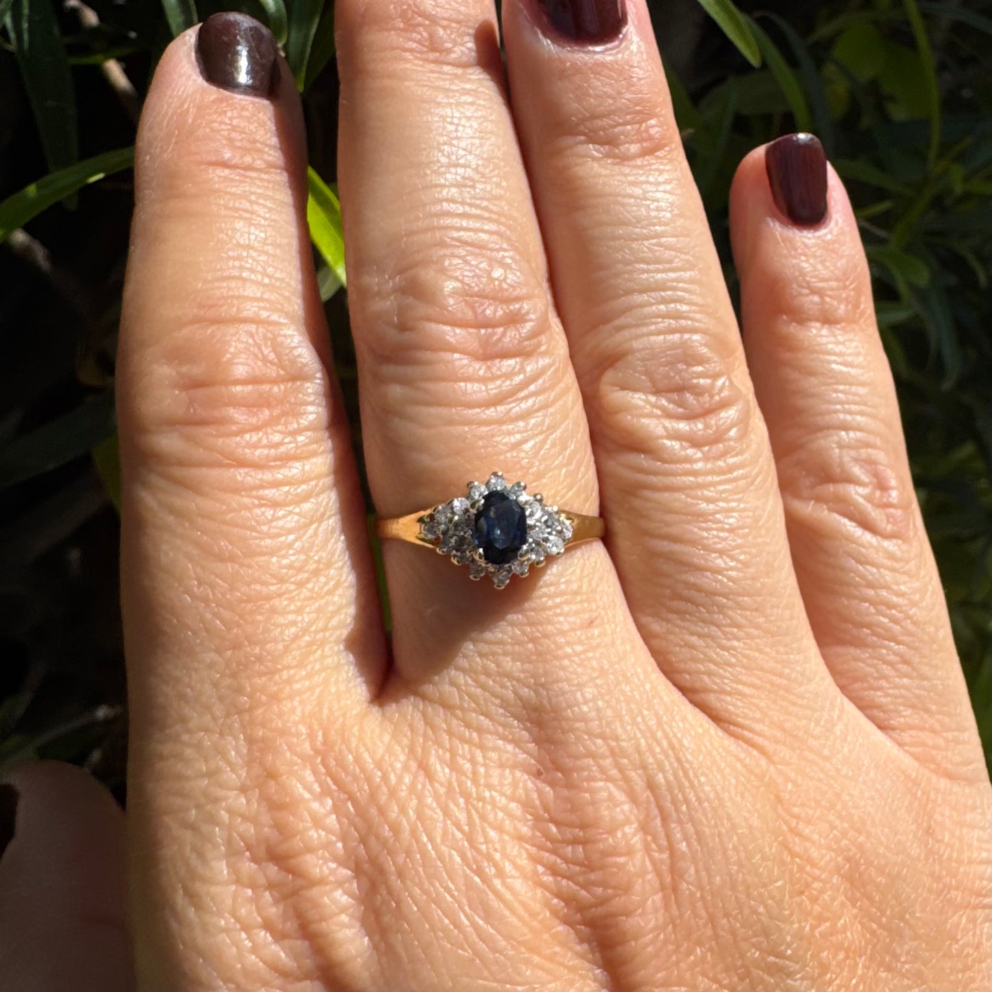 14K gold ring set with an oval blue Sapphire surrounded by sparkling Diamonds