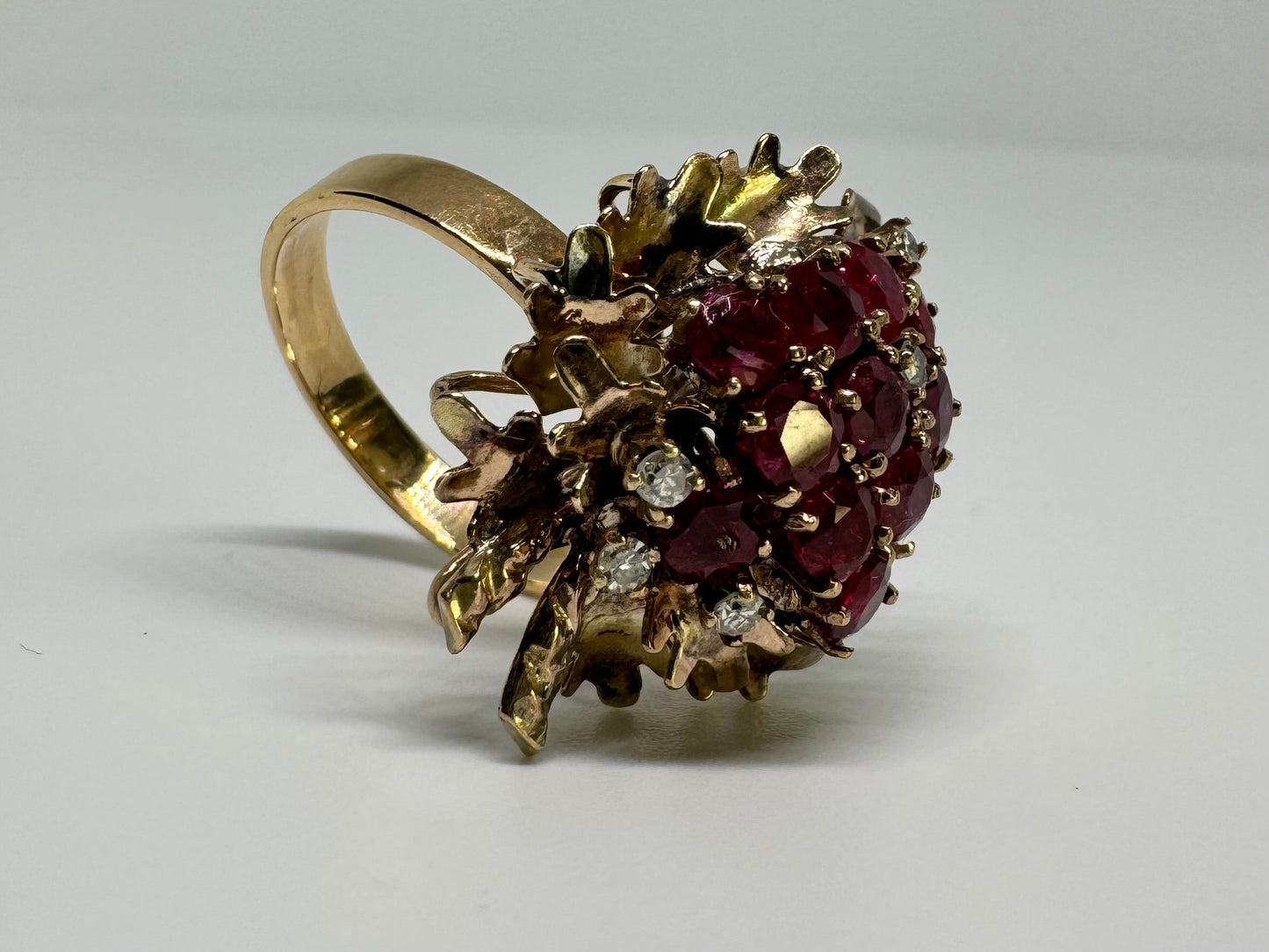 14K gold ring set with a vibrant cluster of deep red rubies and sparkling diamonds.