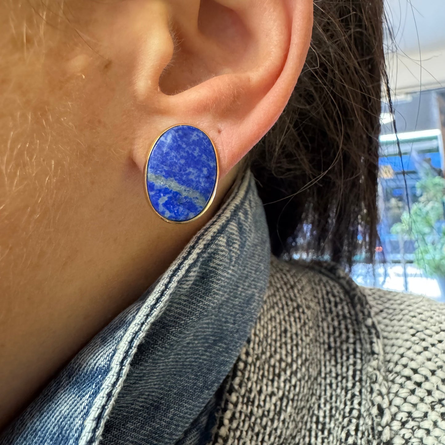 14K gold stud earrings set with polished oval Lapis Lazuli stones in a sleek gold bezel setting.