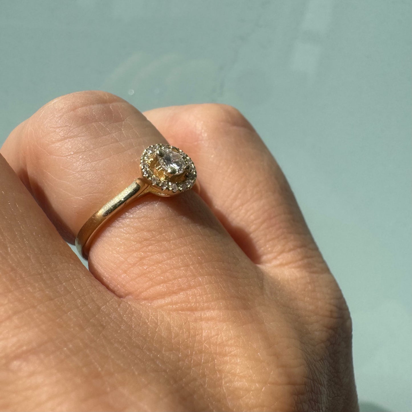 14K gold ring featuring a round central Diamond, surrounded by a sparkling halo of smaller Diamonds.