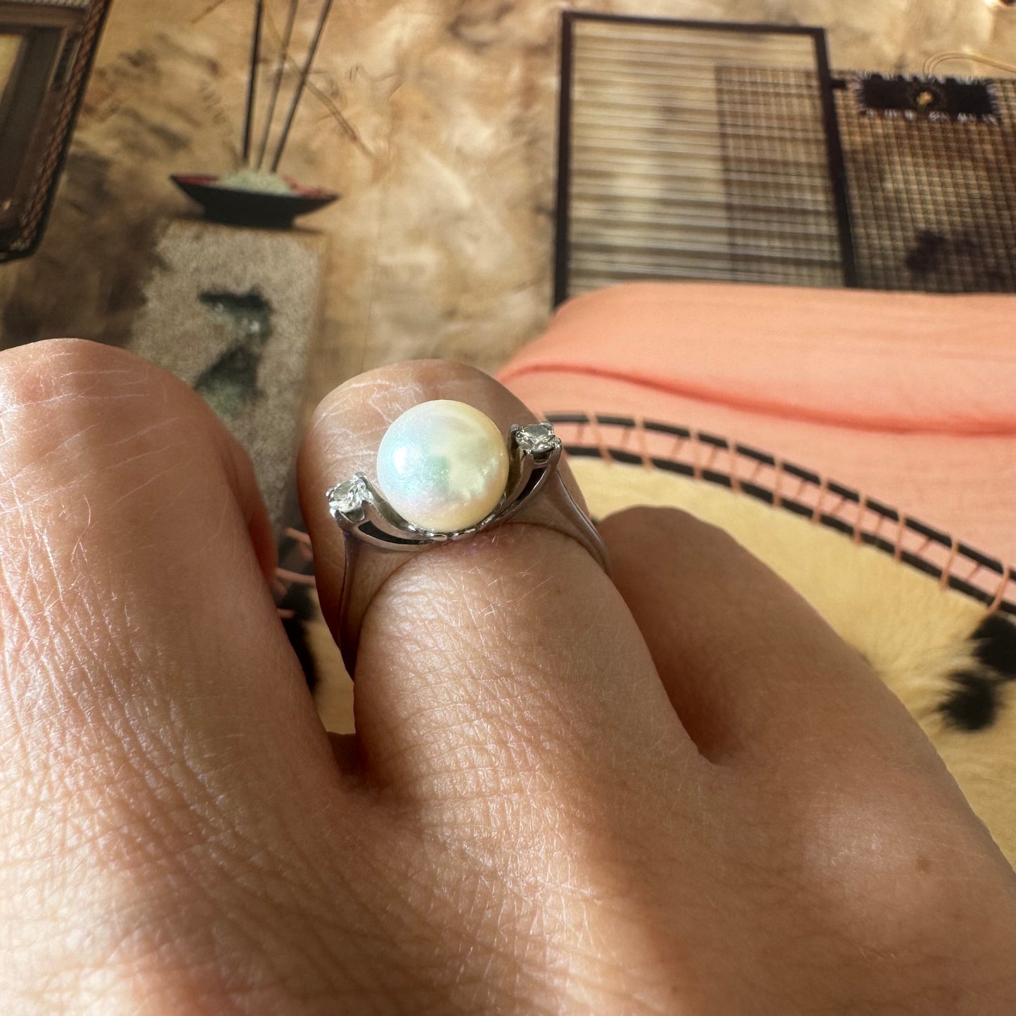 18K gold ring featuring a round Pearl at the center, flanked by two Diamonds.