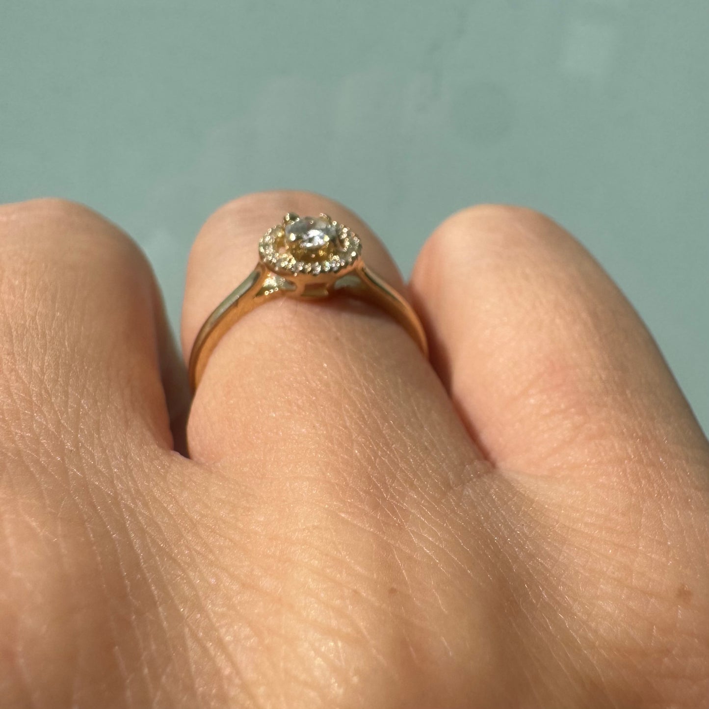 14K gold ring featuring a round central Diamond, surrounded by a sparkling halo of smaller Diamonds.