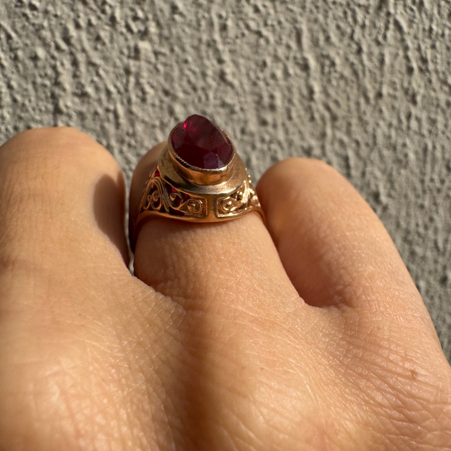 טבעת זהב צהוב 14 קראט משובצת אבן רובי אובלית בצבע אדום עמוק, במסגרת מעוטרת ובעבודת פיליגרן עדינה על הכתפיים.