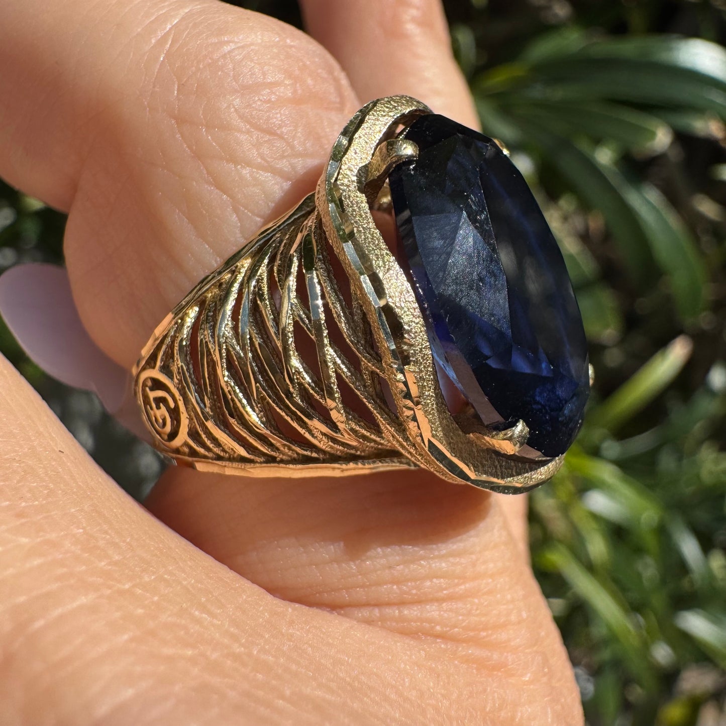14K gold ring set with a deep navy-blue oval Sapphire in a dramatic openwork setting