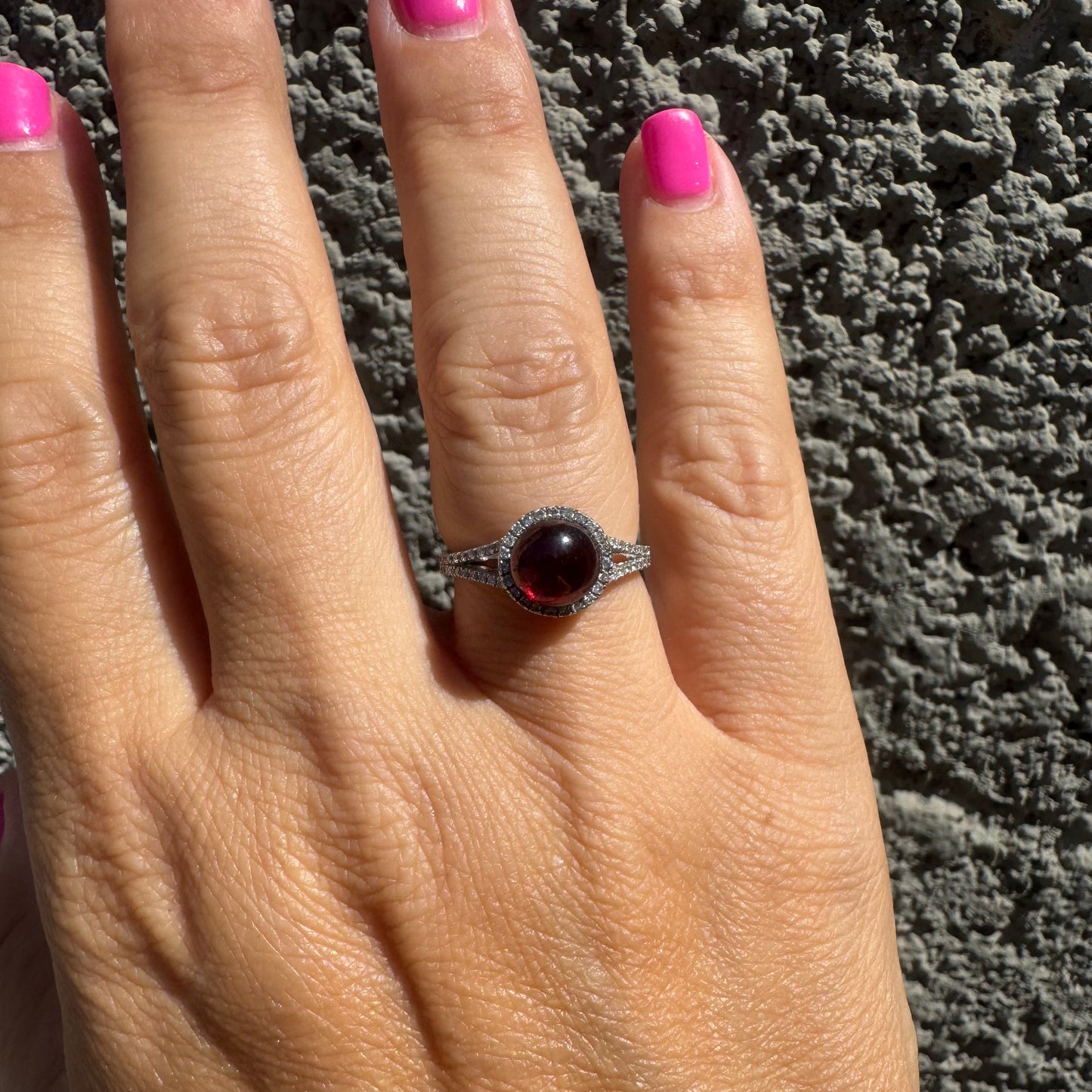 14K gold ring set with a deep red cabochon Garnet, surrounded by a halo of sparkling Diamonds