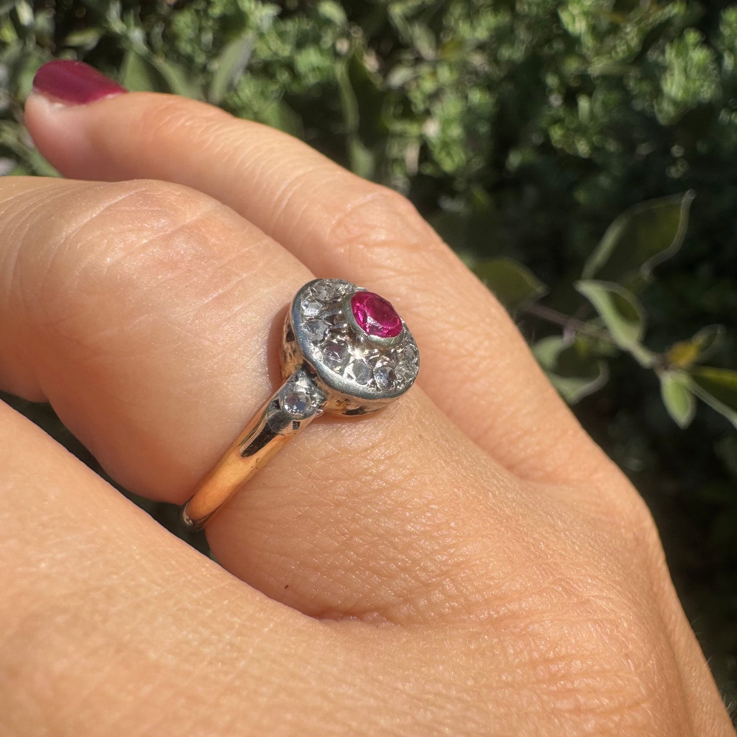 18K gold ring set with a round Ruby at the center, surrounded by a halo of old-cut Diamonds.