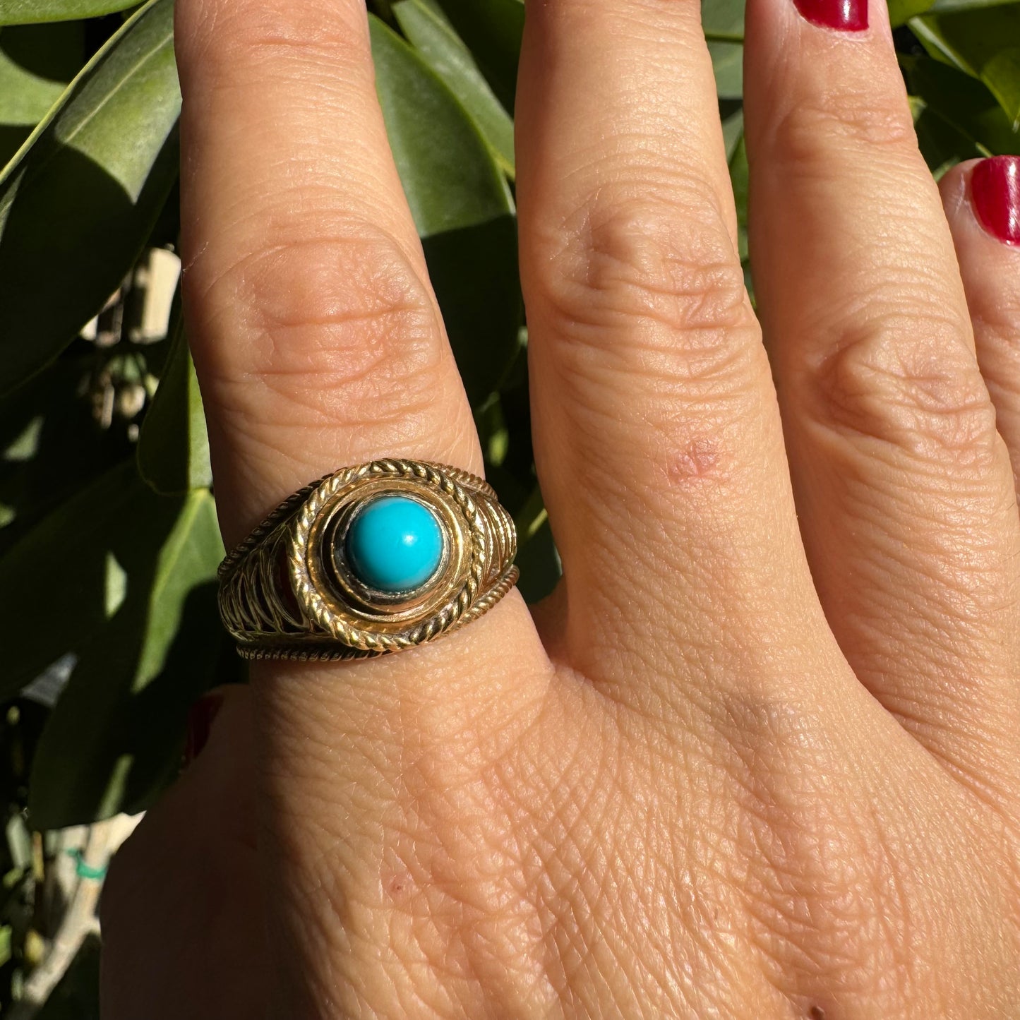 14K gold ring set with a round Turquoise stone at its center framed by a double rope-style bezel