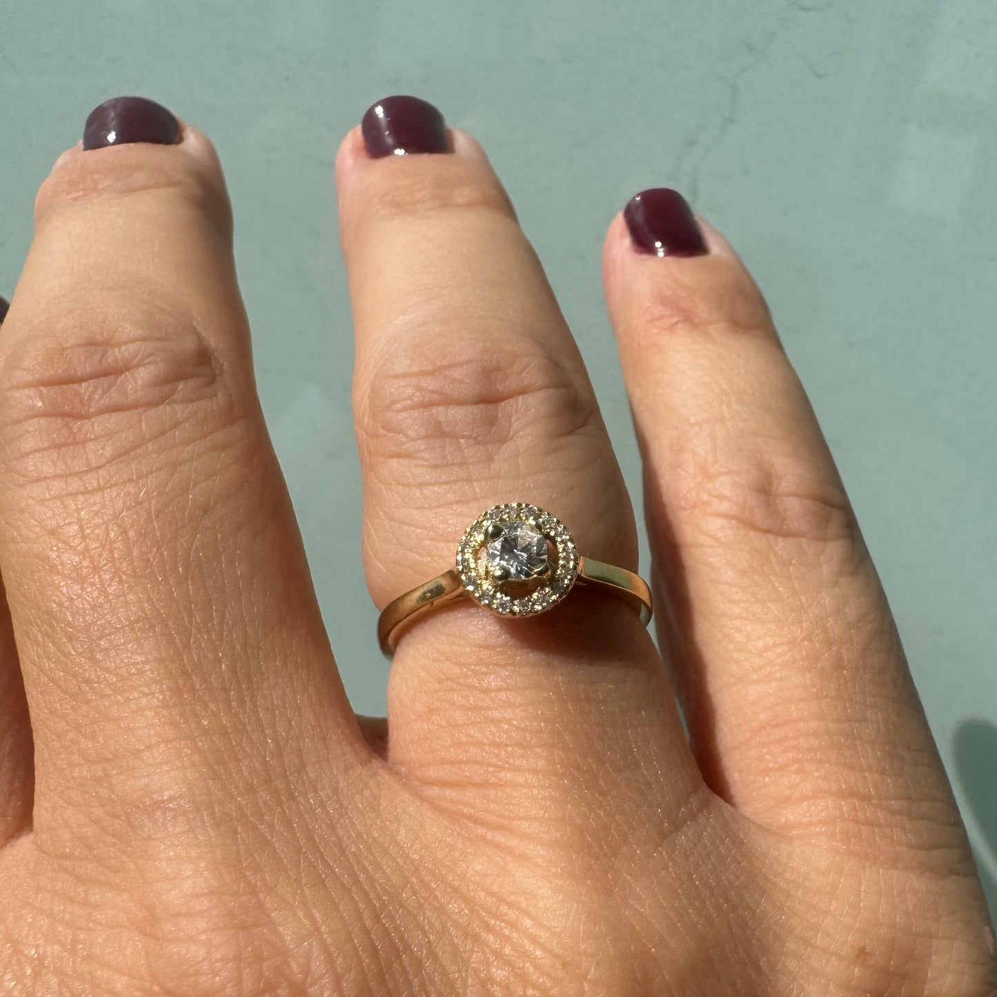 14K gold ring featuring a round central Diamond, surrounded by a sparkling halo of smaller Diamonds.