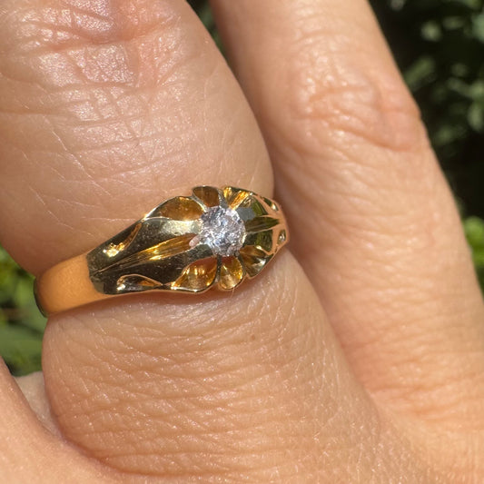 18K gold ring set with a small sparkling diamond at the center.