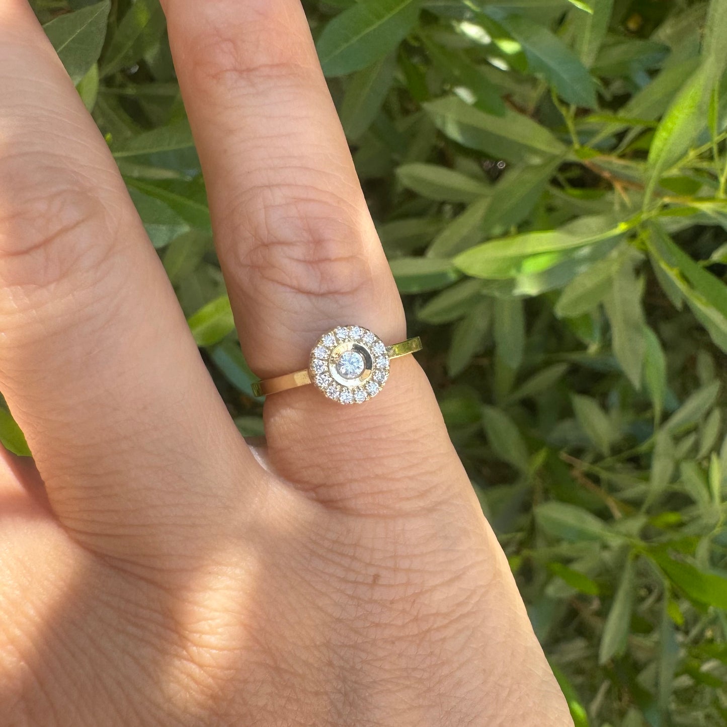 14K gold ring set with a bezel-set central Diamond, surrounded by a sparkling halo of brilliant-cut Diamonds.