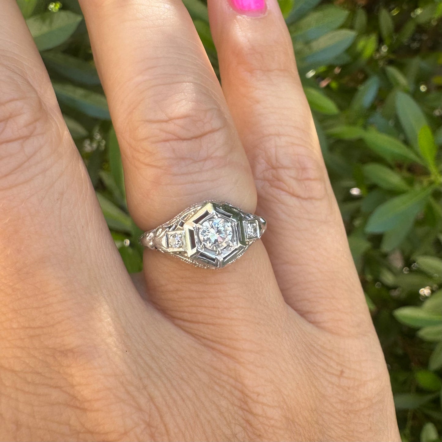 14K gold ring set with a central round diamond, framed by geometric Art Deco details and additional accent stones.