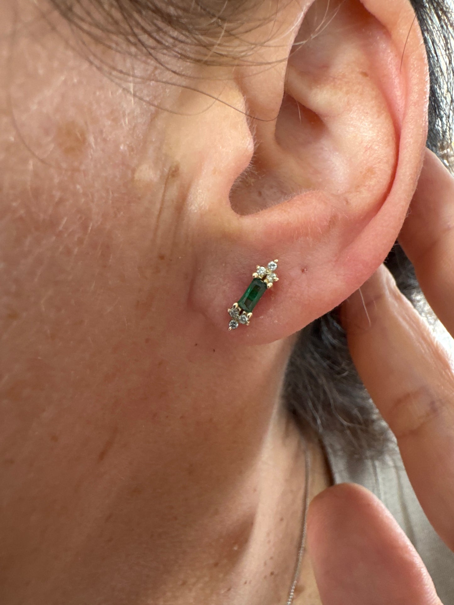 עגילי זהב 14 קראט משובצים אבני אמרלד בחיתוך מלבני ולצידן יהלומים בחיתוך עגול.