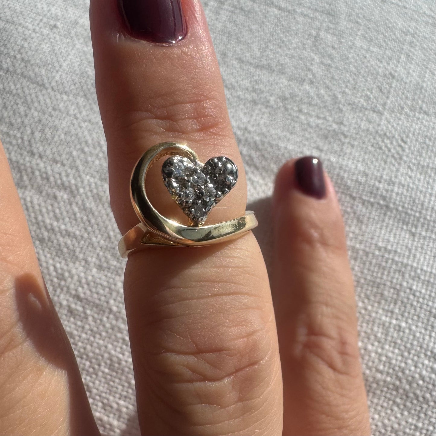 14K gold ring featuring a Diamond-studded heart embraced by a flowing golden curve.