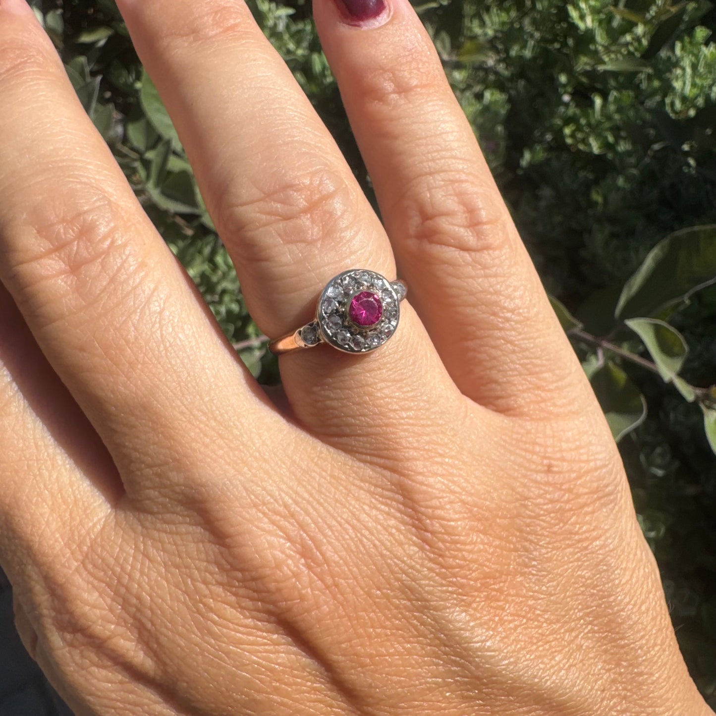 18K gold ring set with a round Ruby at the center, surrounded by a halo of old-cut Diamonds.