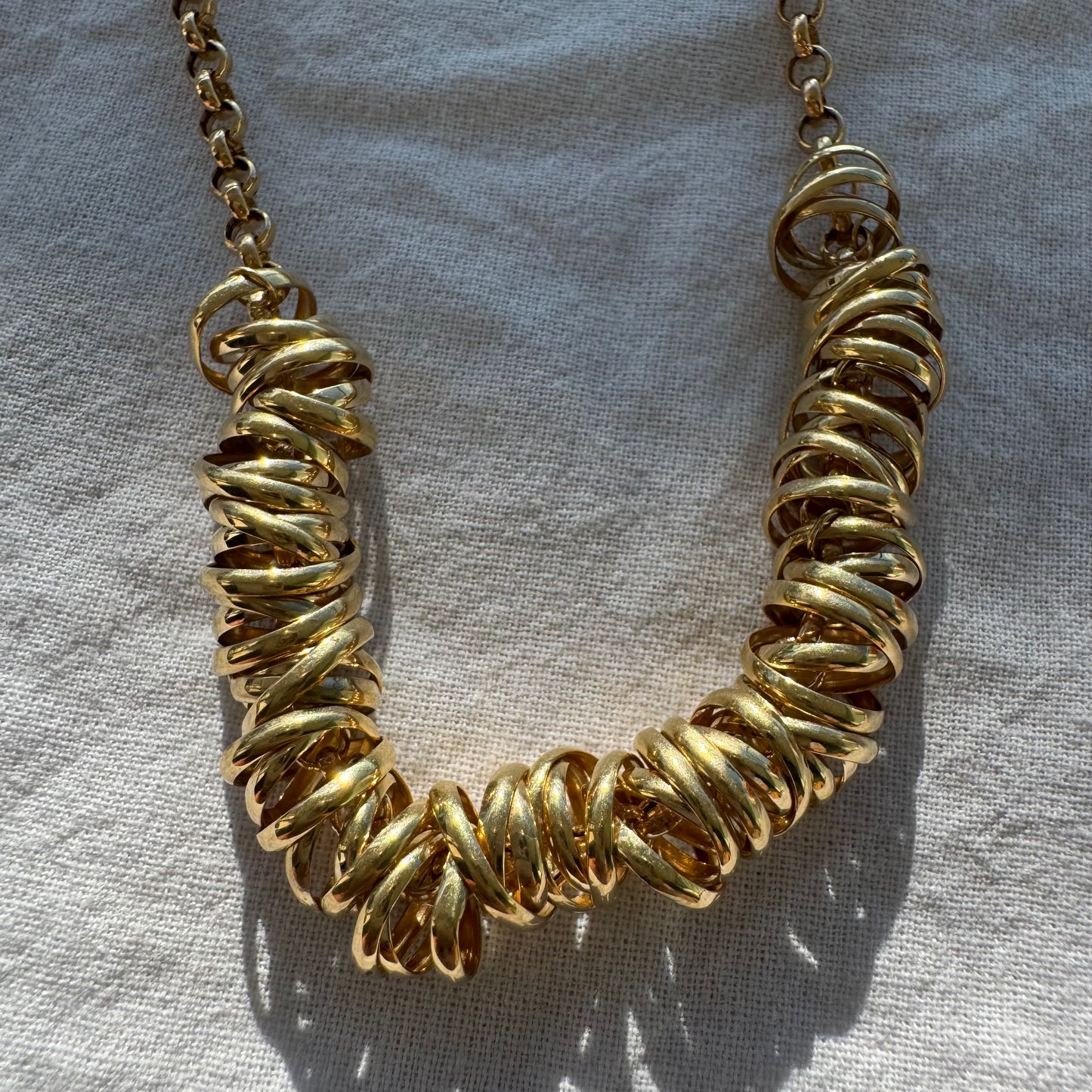 14K gold necklace featuring a series of intertwined gold rings creating a bold and sculptural design.
