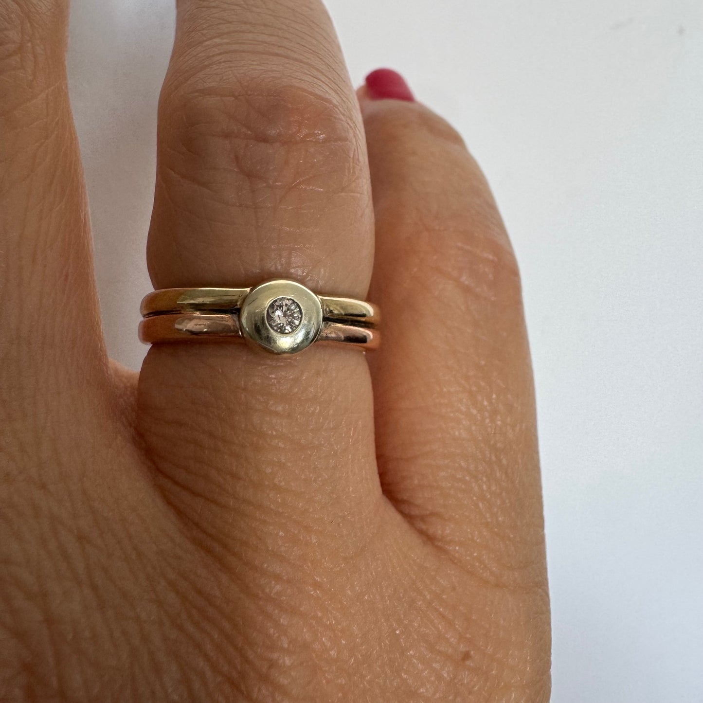 טבעת זהב 10 קראט בעיצוב מינימליסטי ונקי, משובצת יהלום מרכזי במסגרת חלקה (Bezel).