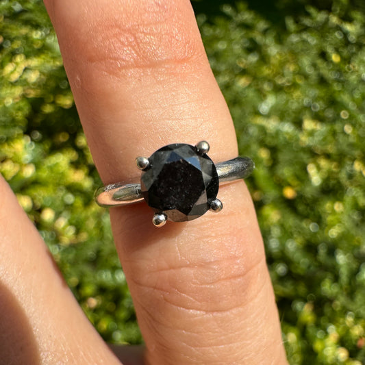 טבעת סוליטר זהב לבן 10 קראט אלגנטית ובעלת נוכחות, משובצת ביהלום שחור בחיתוך עגול במסגרת קלאסית בעלת ארבע שיניים מזהב לבן.