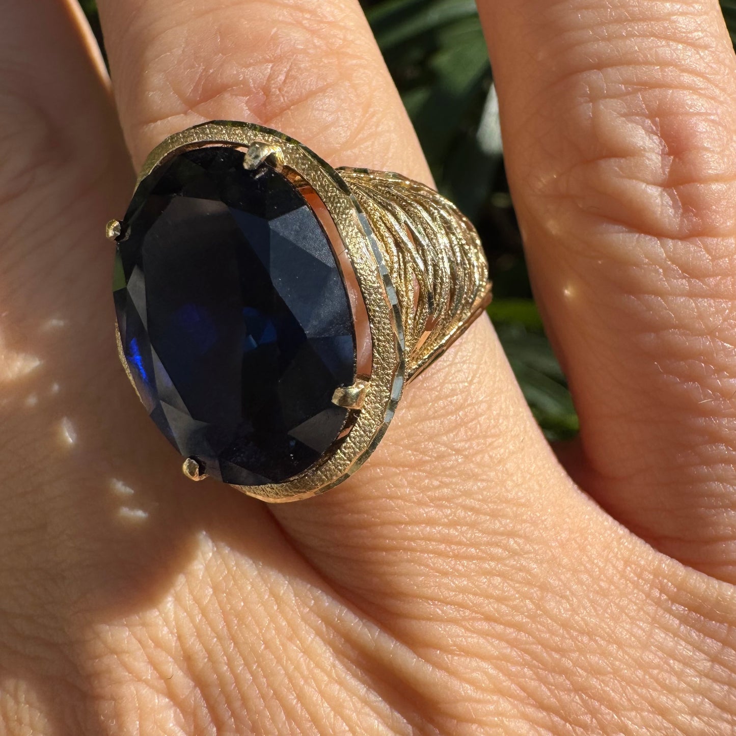14K gold ring set with a deep navy-blue oval Sapphire in a dramatic openwork setting