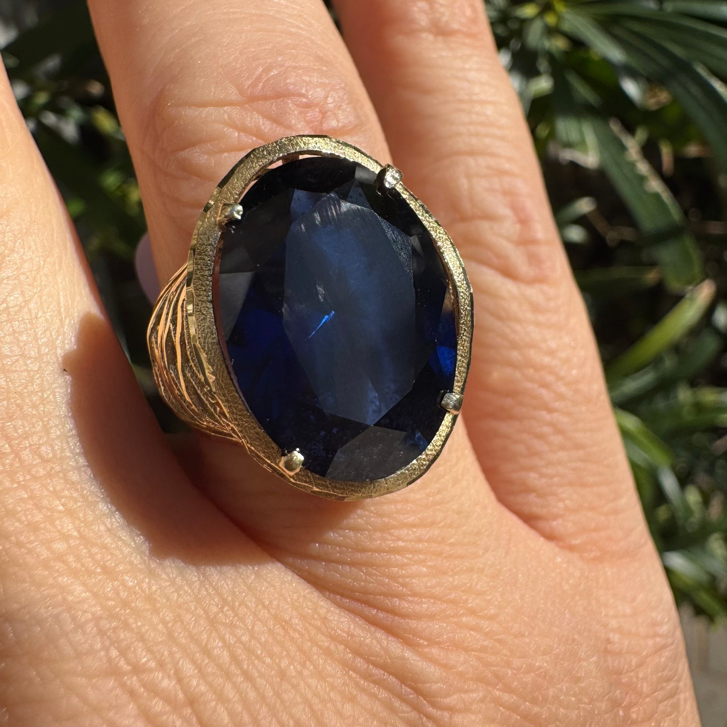 טבעת זהב צהוב 14 קראט משובצת אבן ספיר בחיתוך אובלי, ובסיס מזהב עם עיטורי תבליט דמויי עלים או גלים