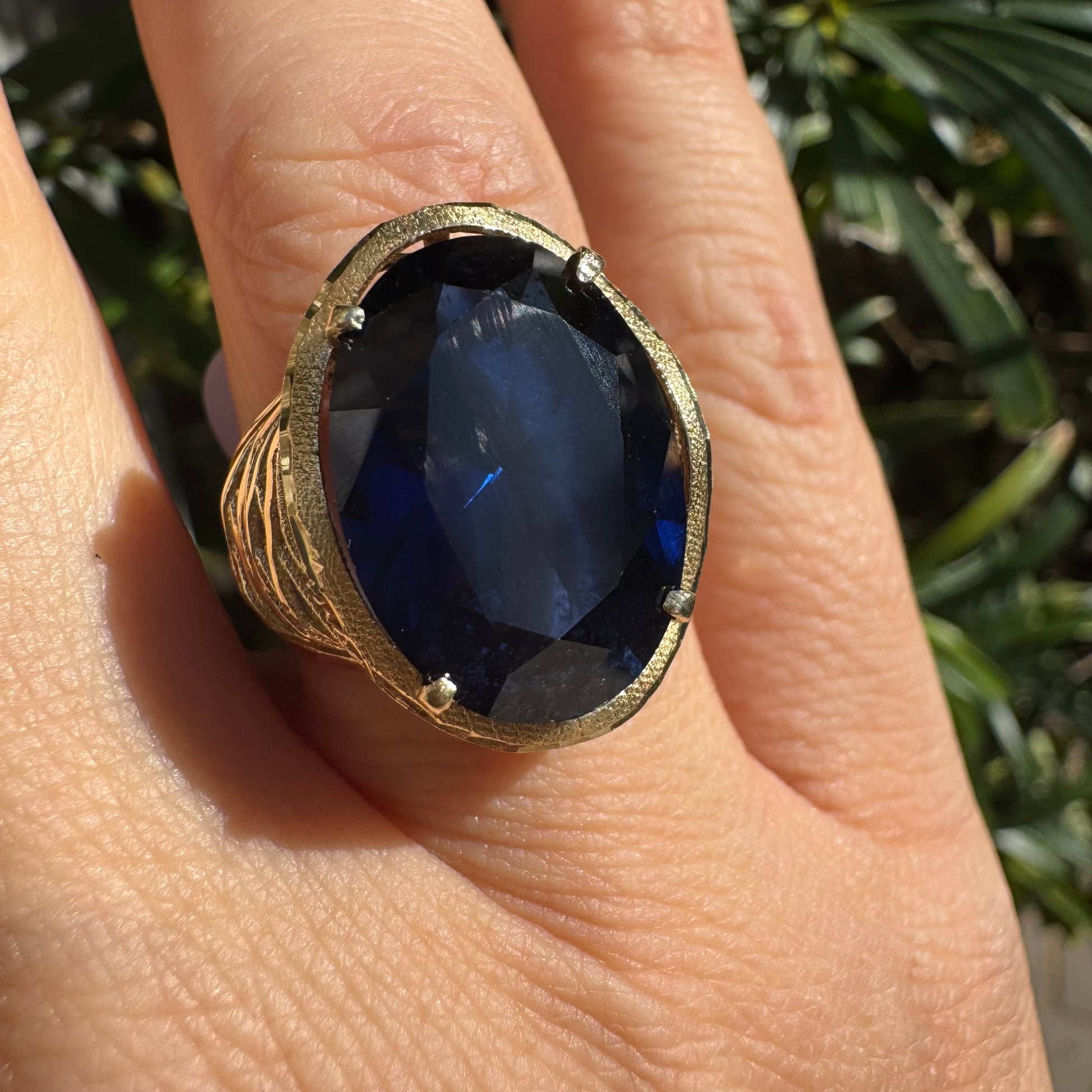 טבעת זהב צהוב 14 קראט משובצת אבן ספיר בחיתוך אובלי, ובסיס מזהב עם עיטורי תבליט דמויי עלים או גלים