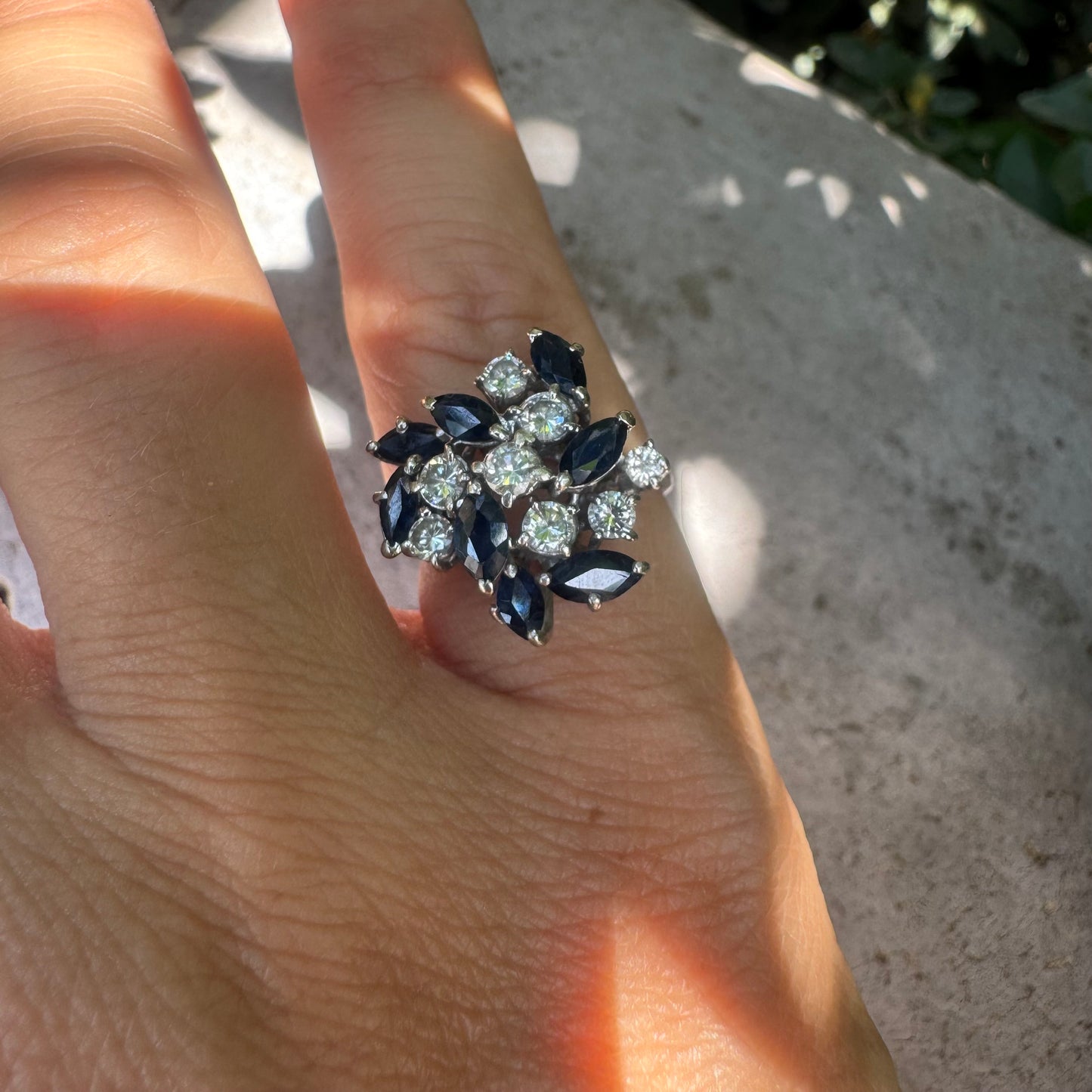 18K gold cluster ring featuring marquise-cut blue sapphires and round brilliant Diamonds arranged in a floral design.