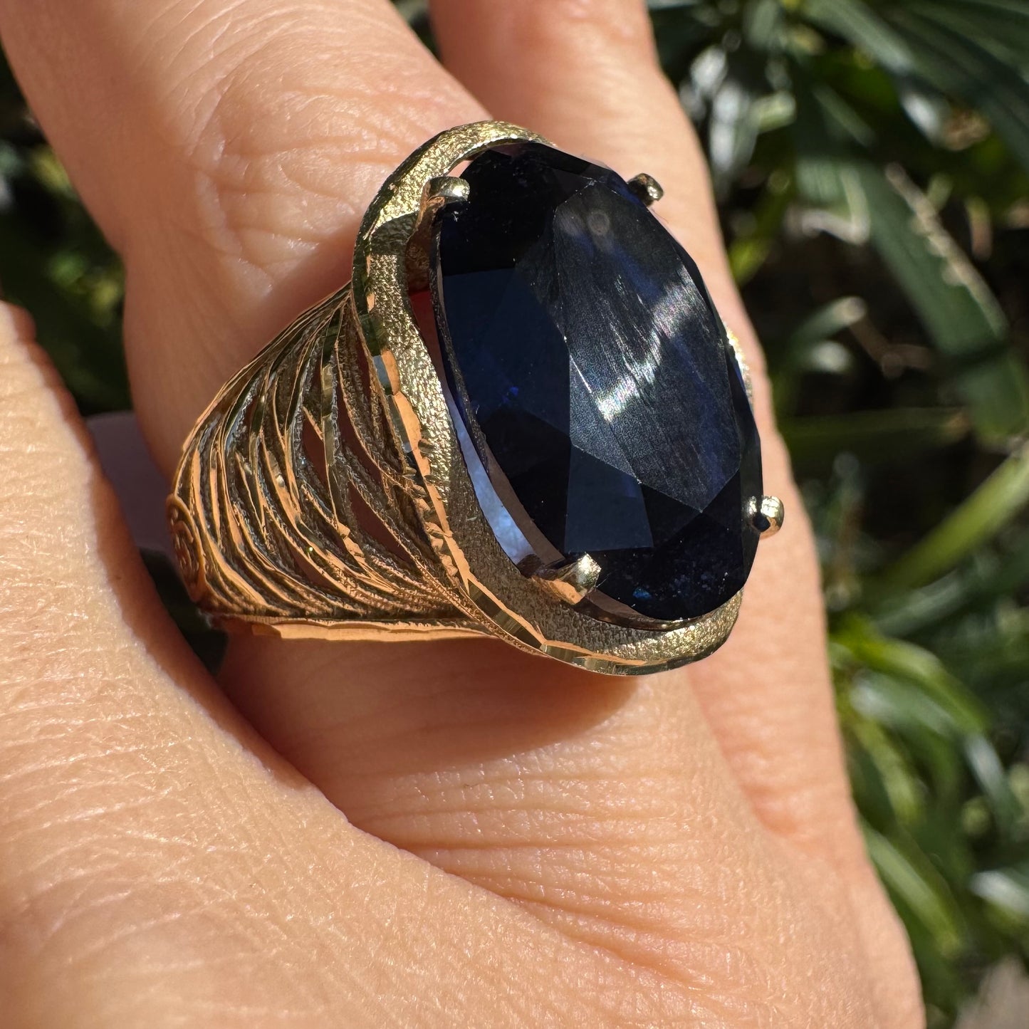 14K gold ring set with a deep navy-blue oval Sapphire in a dramatic openwork setting