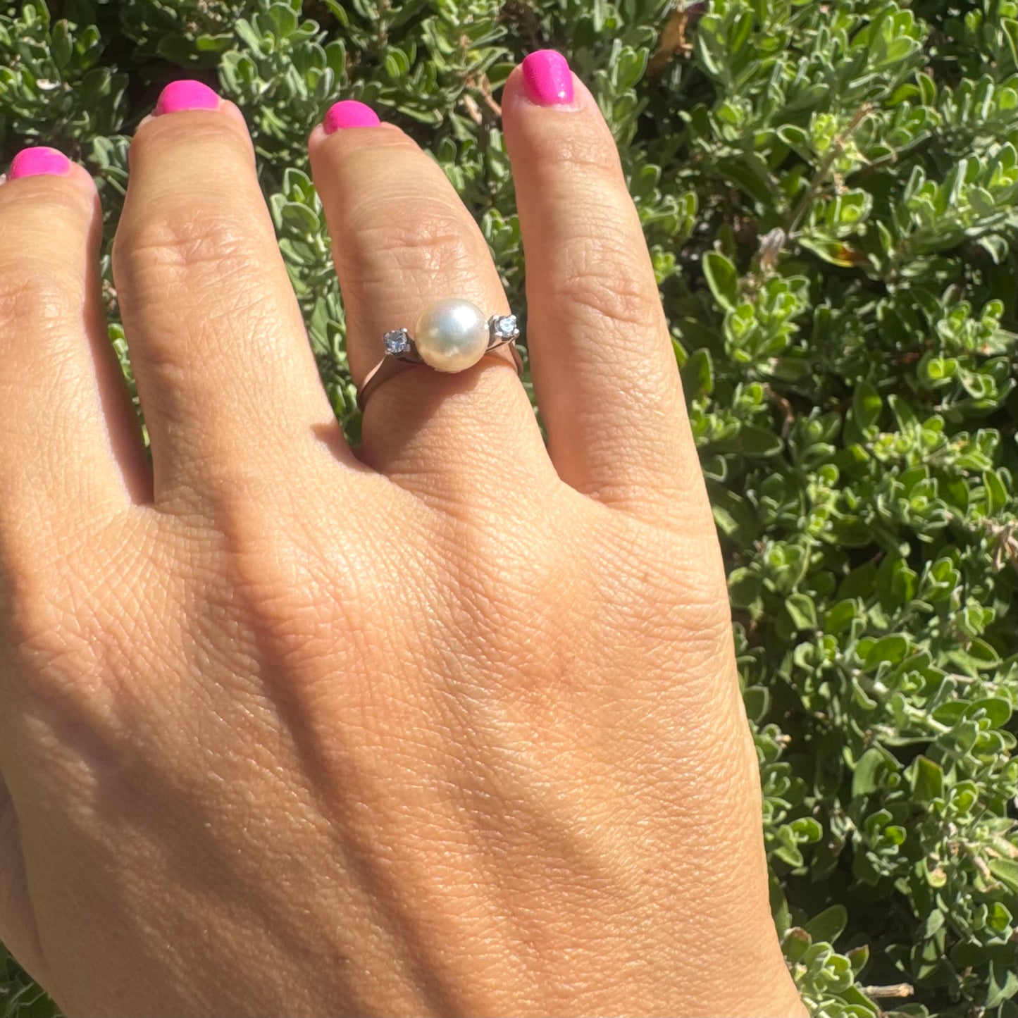 18K gold ring featuring a round Pearl at the center, flanked by two Diamonds.