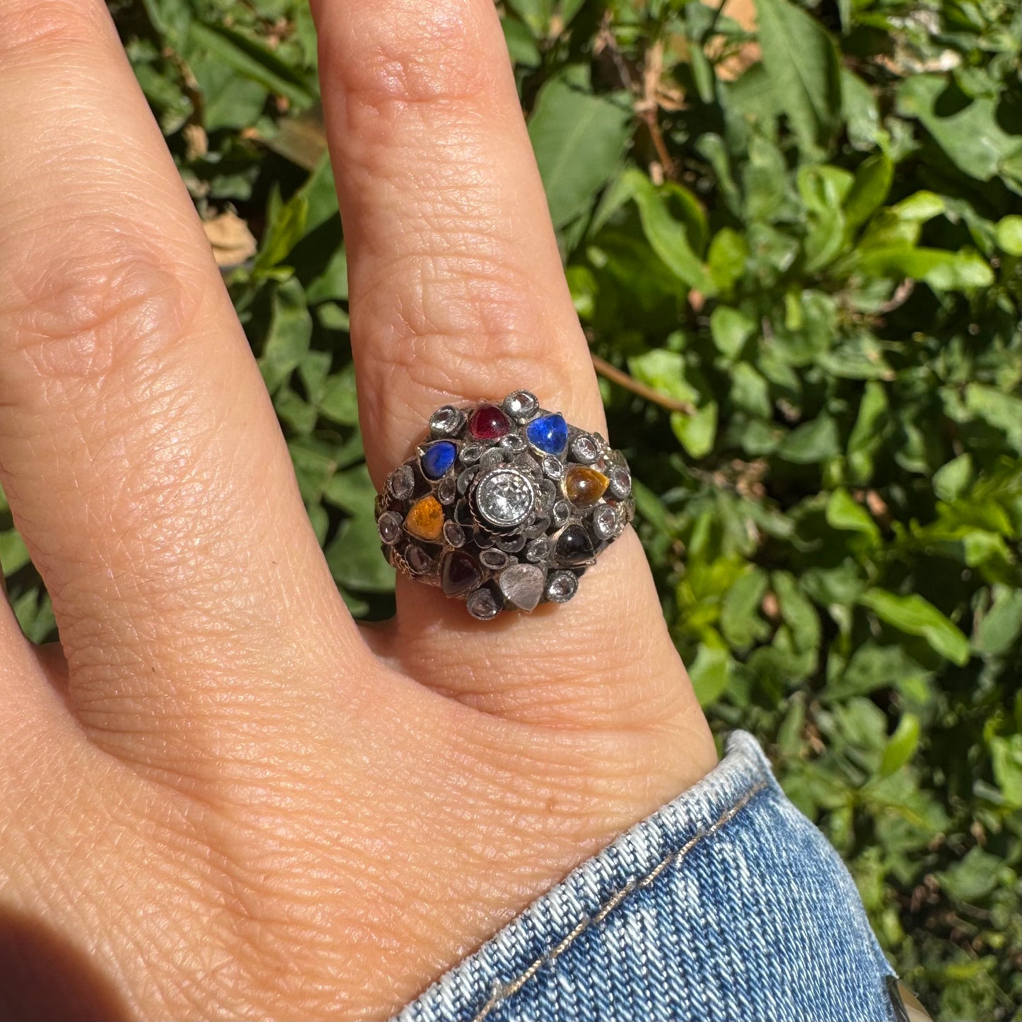 14K gold ring set with a central transparent gemstone surrounded by a vibrant mosaic of colorful gemstones -set in an ornate, handcrafted design