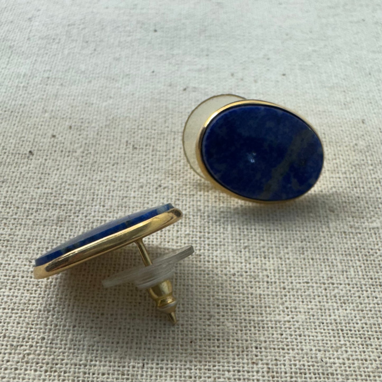 14K gold stud earrings set with polished oval Lapis Lazuli stones in a sleek gold bezel setting.