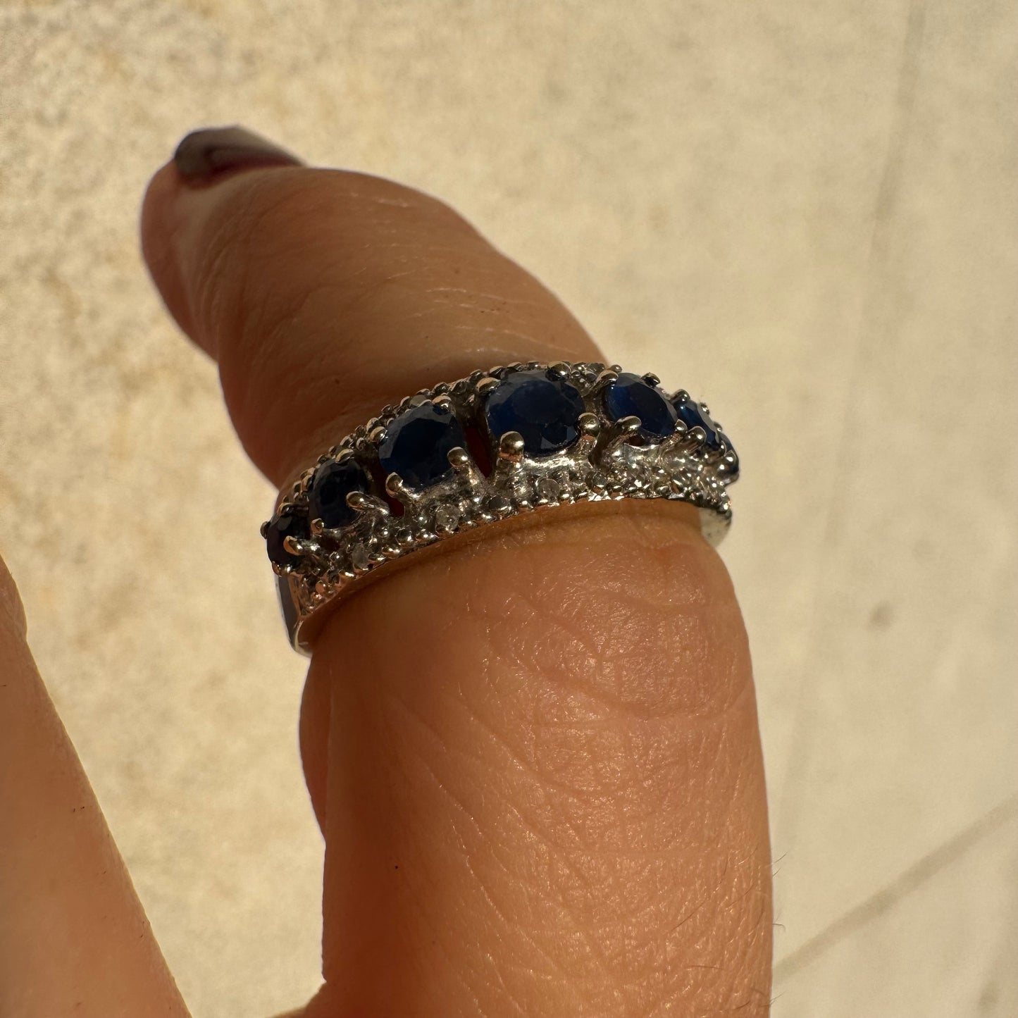 18K gold ring set with deep blue sapphires in a classic round cut, framed by two shimmering rows of brilliant Diamonds.