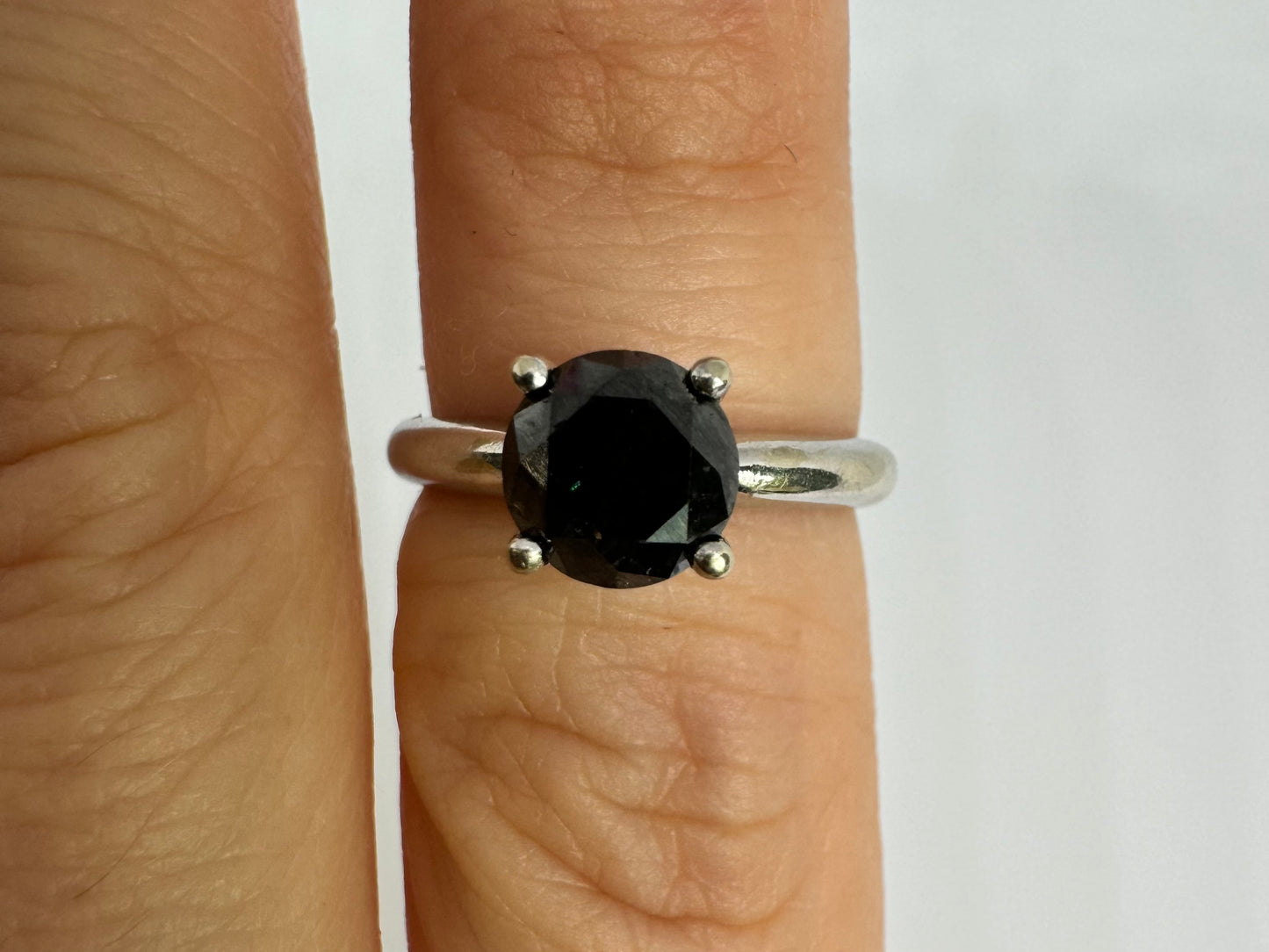 טבעת סוליטר זהב לבן 10 קראט אלגנטית ובעלת נוכחות, משובצת ביהלום שחור בחיתוך עגול במסגרת קלאסית בעלת ארבע שיניים מזהב לבן.