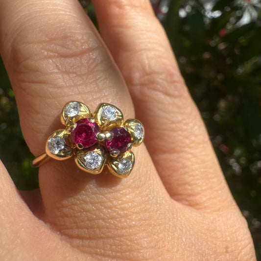 טבעת זהב צהוב 18 קראט בעיצוב פרח, משובצת בשתי אבני רובי אדומות ויהלומים מסביב.