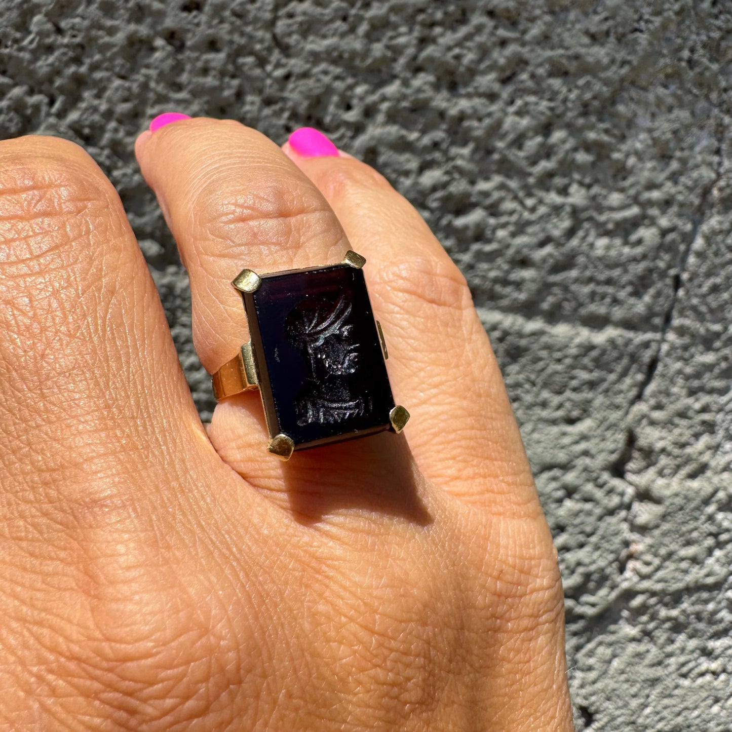 18K gold ring set with a carved dark stone featuring a classical warrior profile.