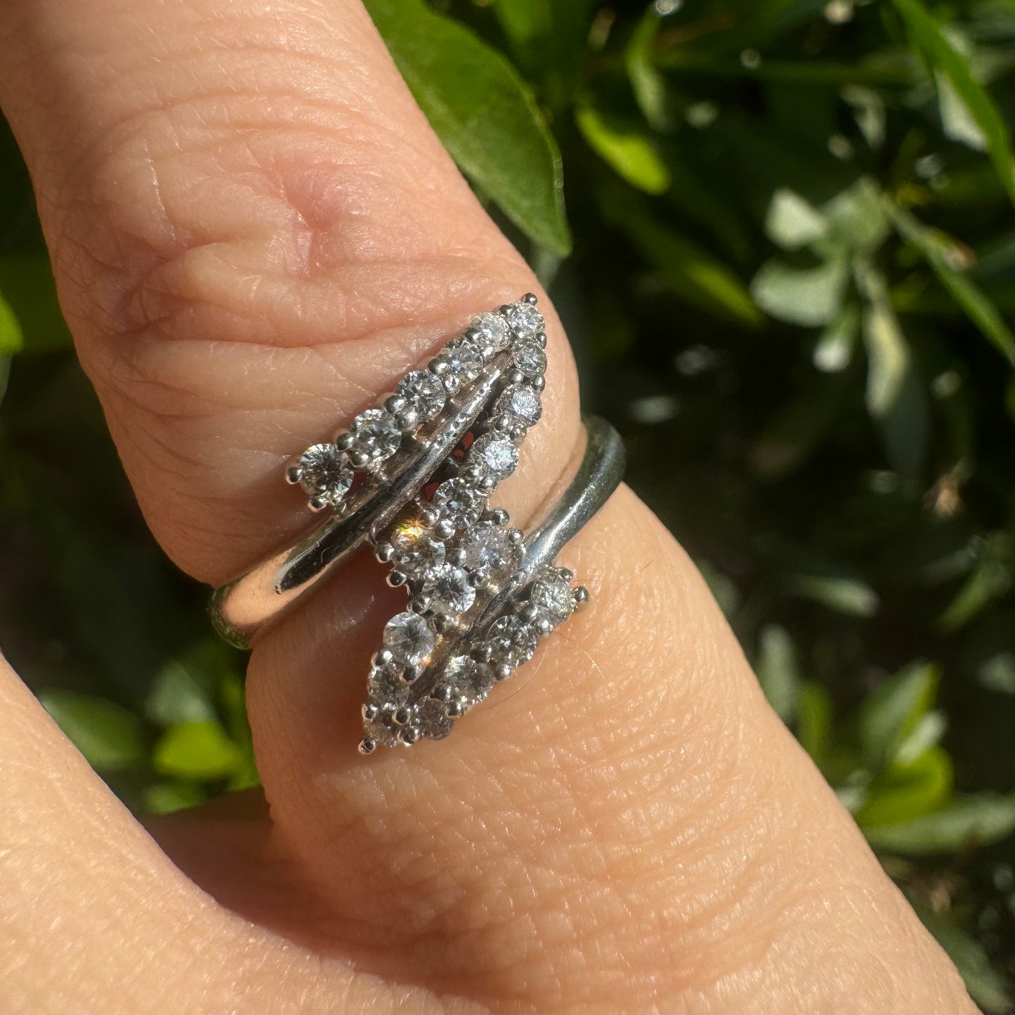 טבעת זהב לבן 14 קראט בעיצוב פתוח, עם שתי שורות מעוגלות של יהלומים נוצצים, המצטלבות זו בזו בצורה אלגנטית