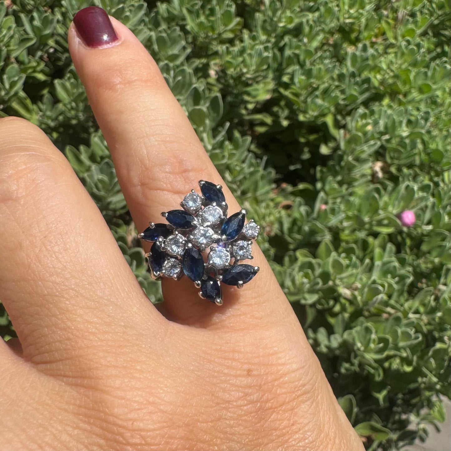 18K gold cluster ring featuring marquise-cut blue sapphires and round brilliant Diamonds arranged in a floral design.