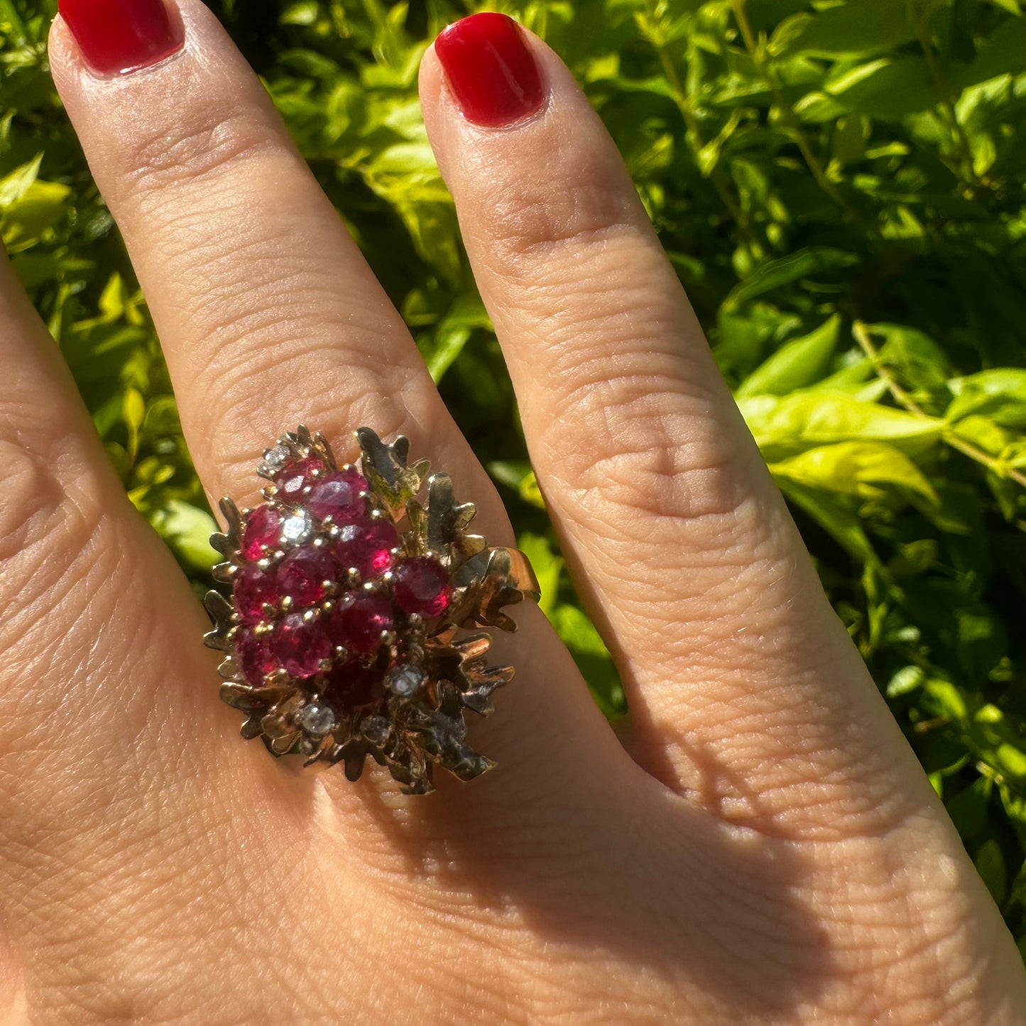 14K gold ring set with a vibrant cluster of deep red rubies and sparkling diamonds.