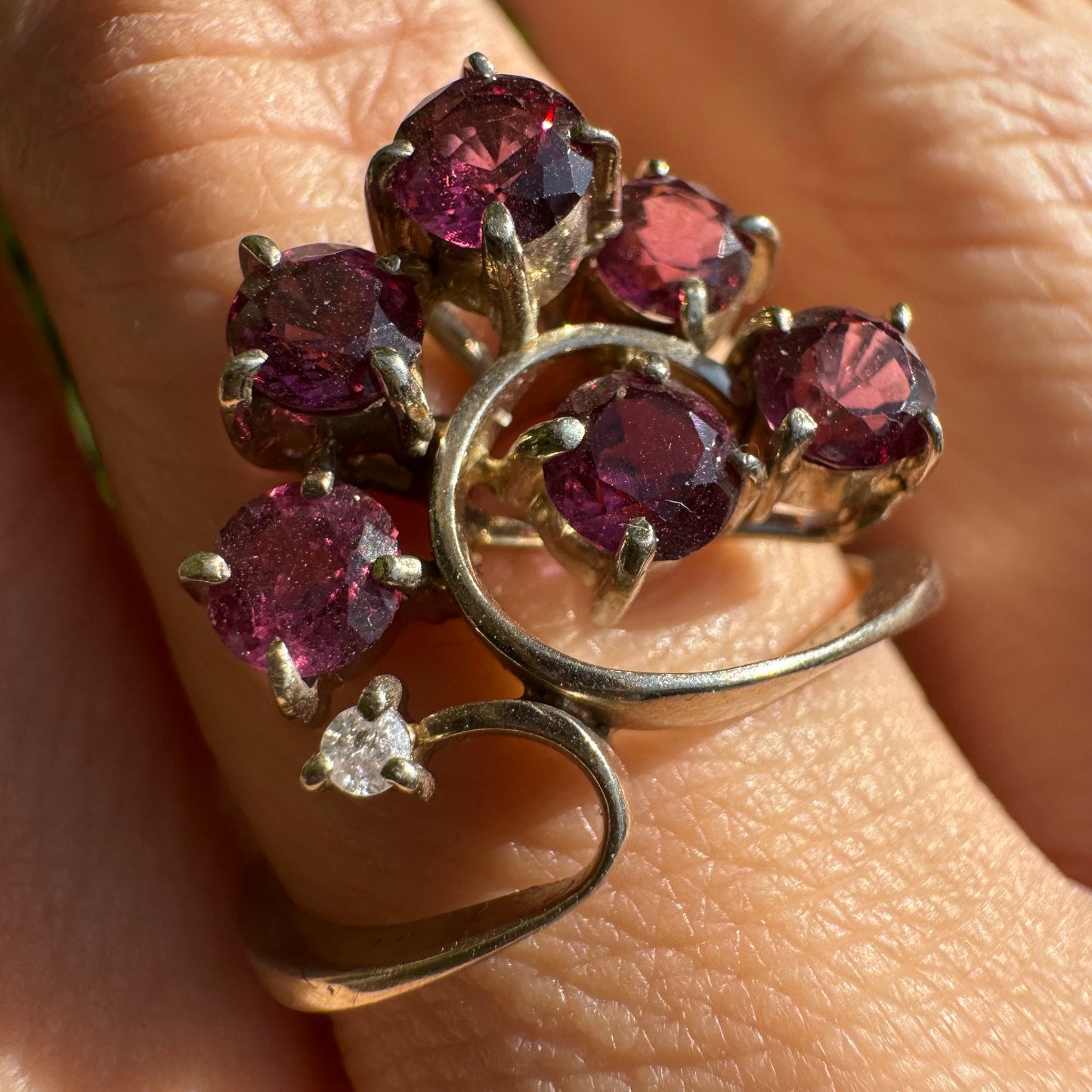 14K gold ring with an open, flowing design, set with multiple pink Tourmaline stones and accented by a Diamond