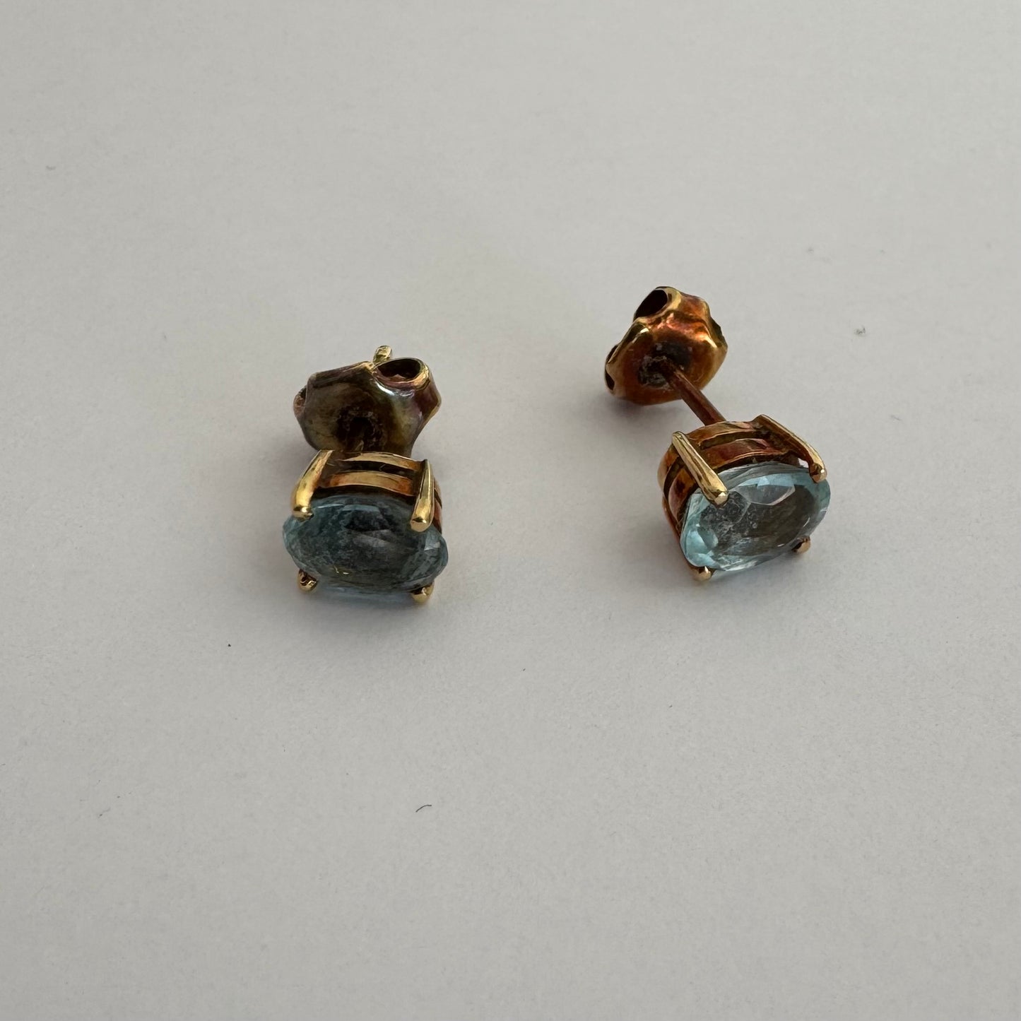 18K gold stud earrings set with oval-cut Aquamarines.