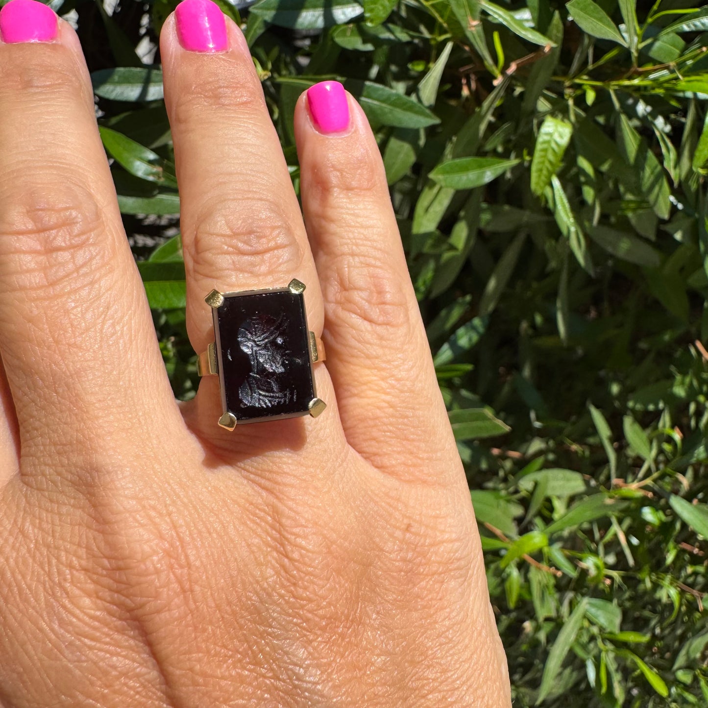 18K gold ring set with a carved dark stone featuring a classical warrior profile.