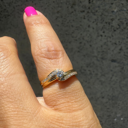 טבעת זהב צהוב 14 קראט עדינה עם עיצוב קלאסי ואלגנטי עם שיבוץ של יהלומים קטנים לאורך החישוק ובמרכזה יהלום עגול סוליטר באחיזה של ארבע שיניים.