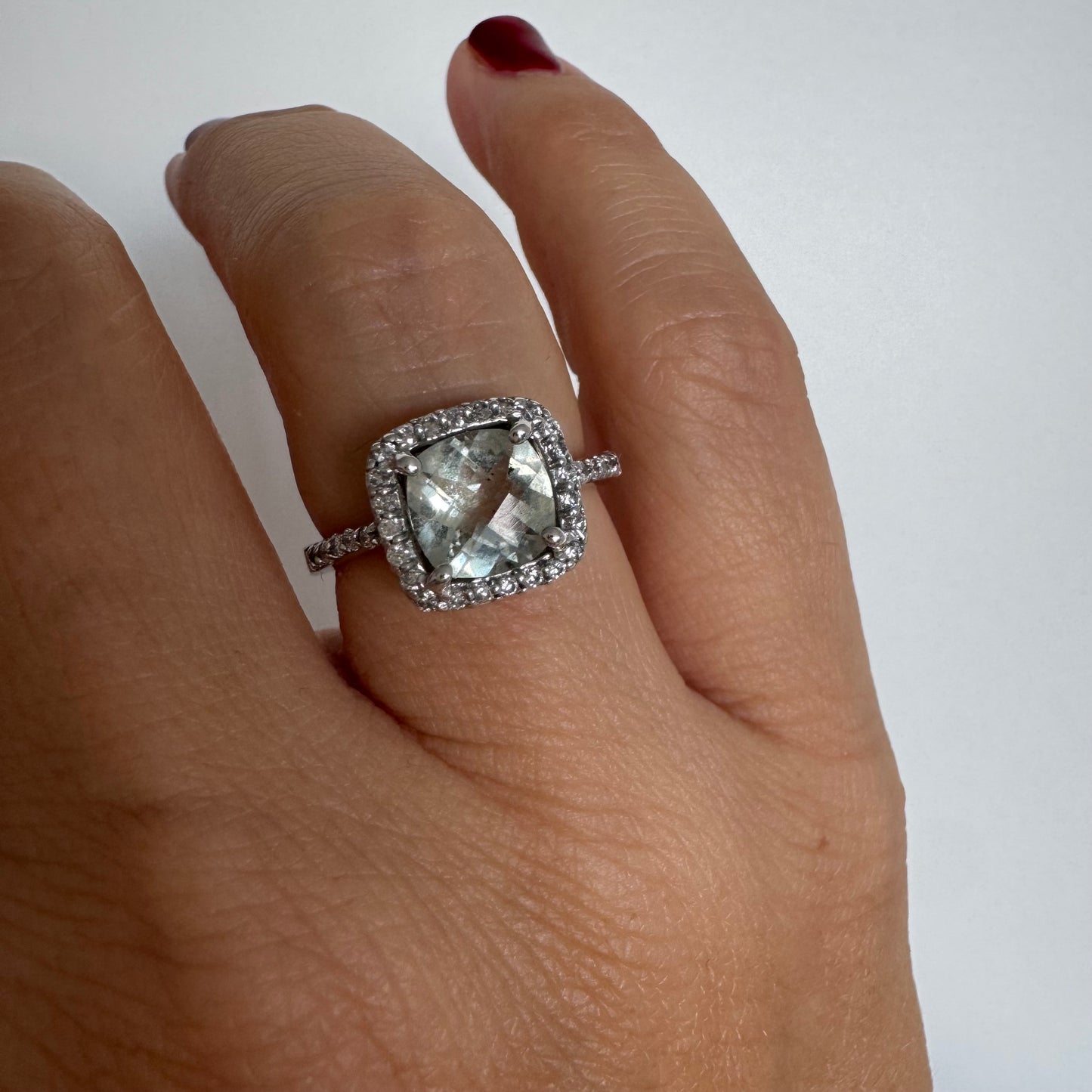 טבעת זהב לבן 14 קראט משובצת באבן אקוומרין בגוון תכלת ומוקפת במסגרת כפולה של יהלומים עגולים מנצנצים.